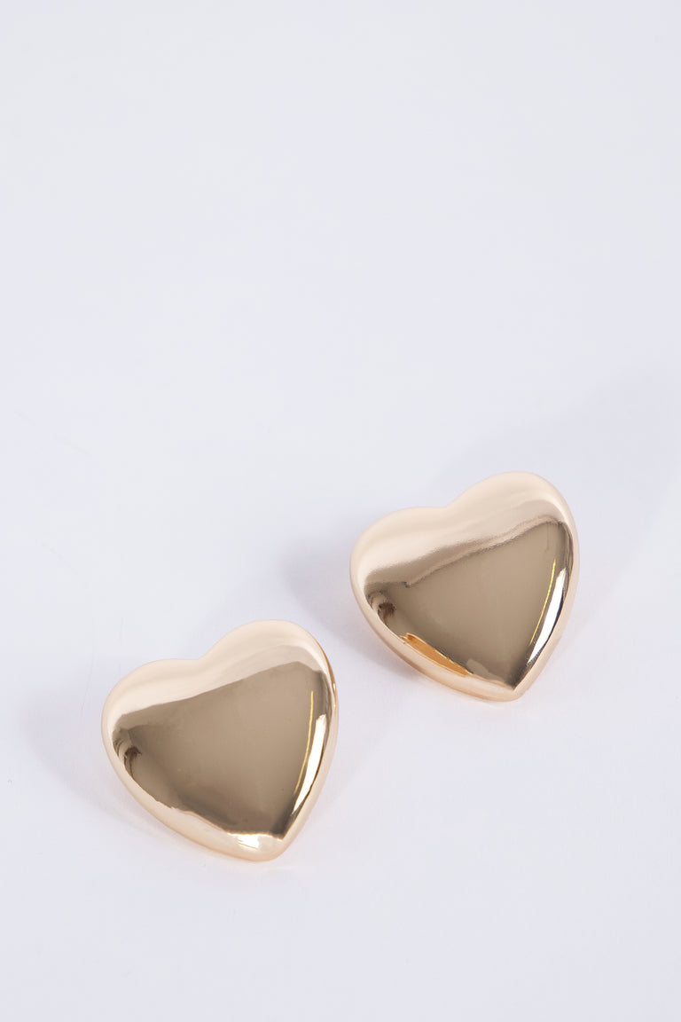 Rose gold oversized heart stud earrings on a light background