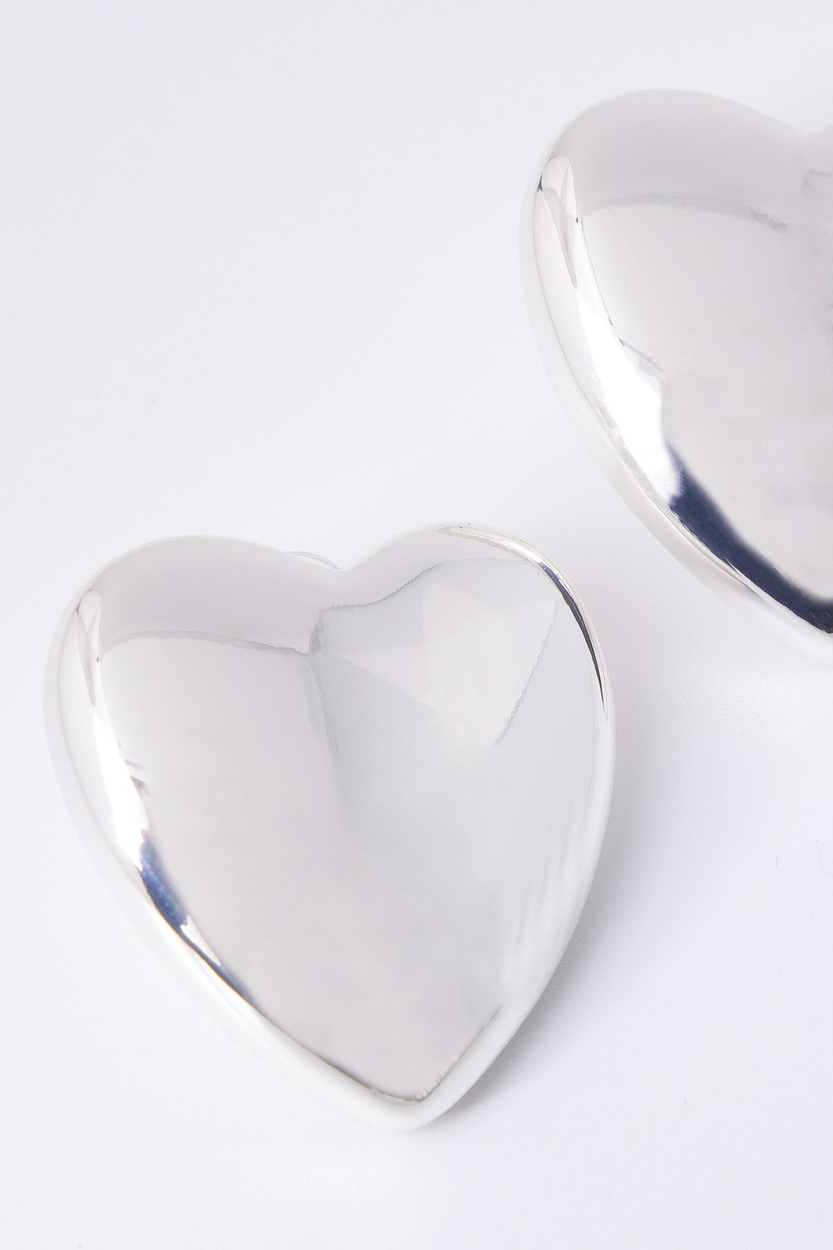 Close up of an oversized silver heart stud earring