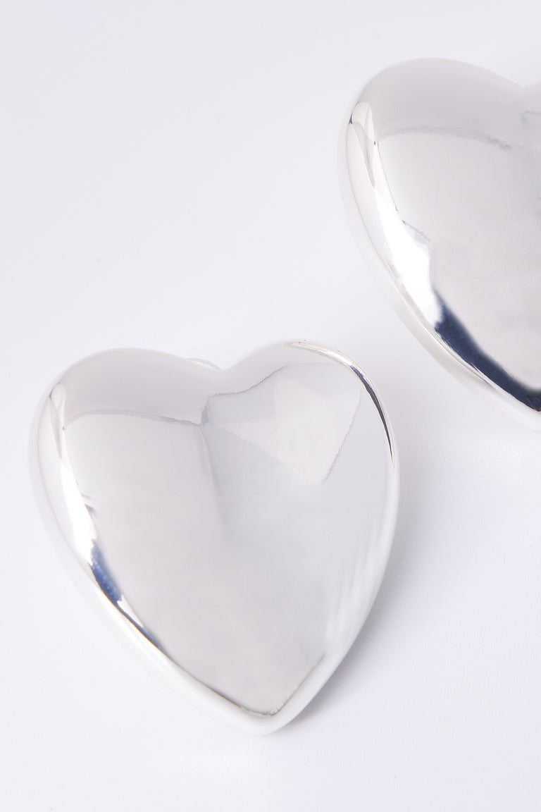 Close up of an oversized silver heart stud earring