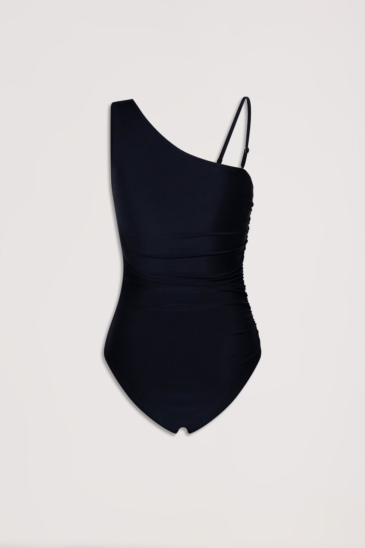 Black matte one shoulder swimsuit with ruched detailing and adjustable strap on one side against plain background