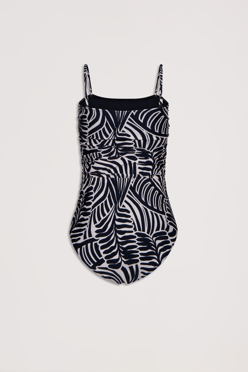 One-piece swimsuit featuring adjustable straps and a bold black and white abstract palm leaf pattern with ruched detailing