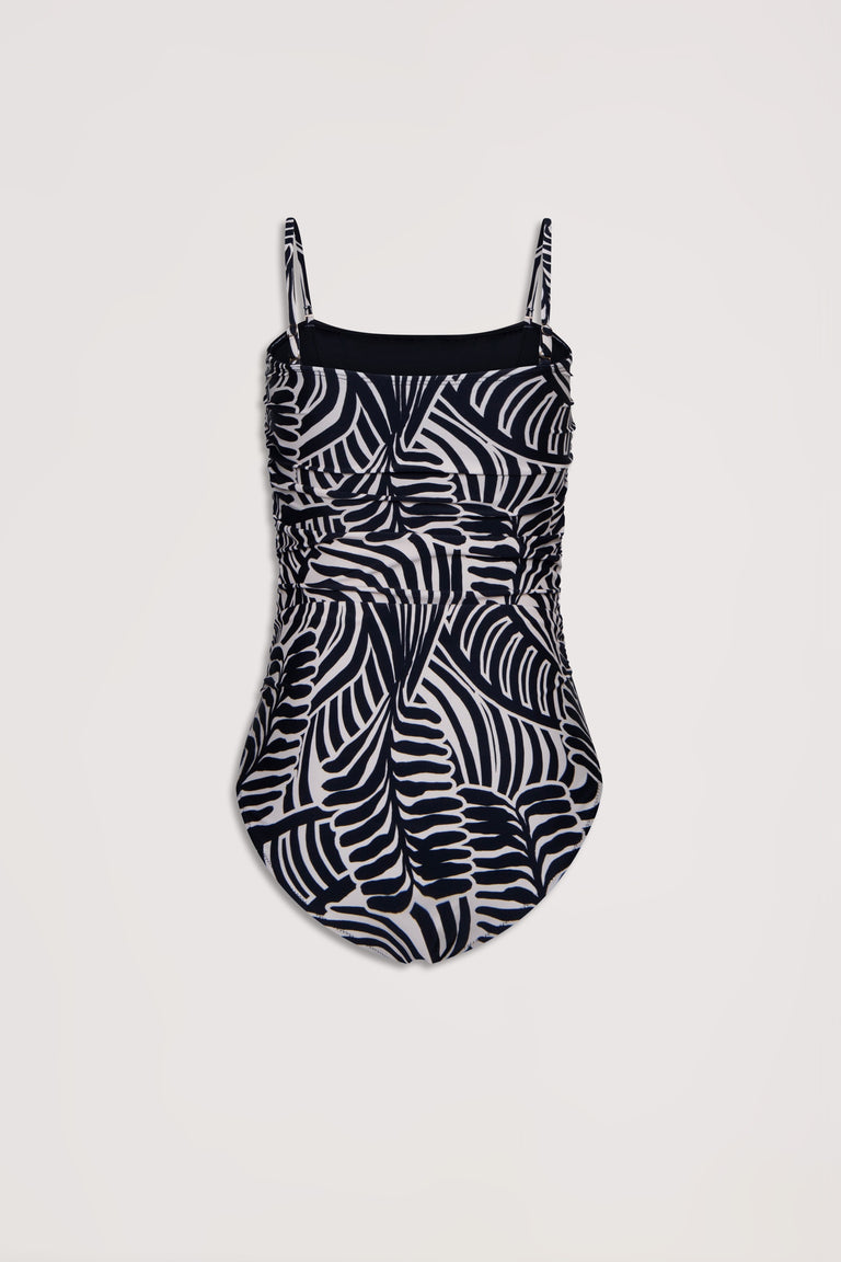 One-piece swimsuit featuring adjustable straps and a bold black and white abstract palm leaf pattern with ruched detailing