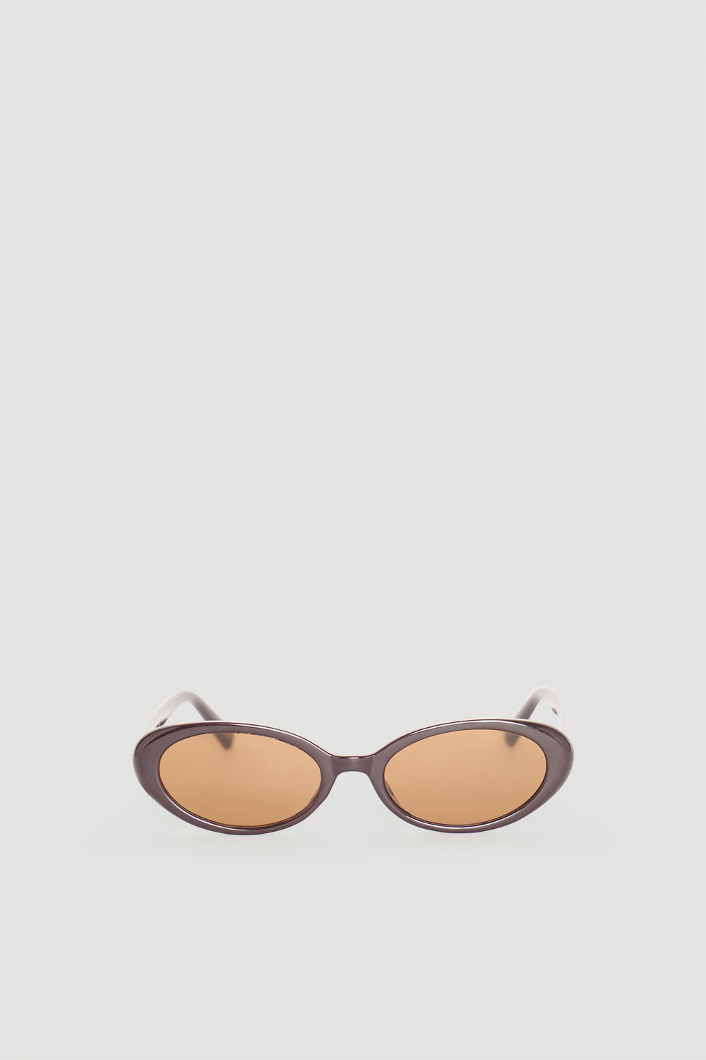 Sleek brown oval sunglasses with warm amber lenses offering a timeless, sophisticated accessory for everyday style.