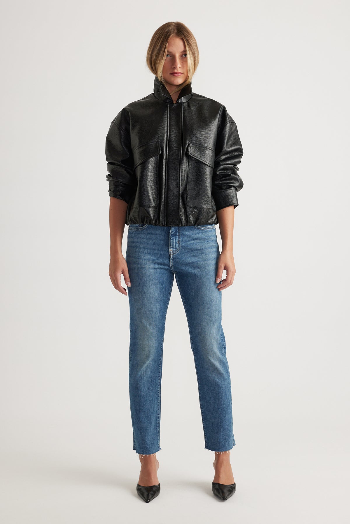 Front view of woman wearing Becky Straight Leg Jean in classic blue denim paired with black faux leather jacket by Decjuba