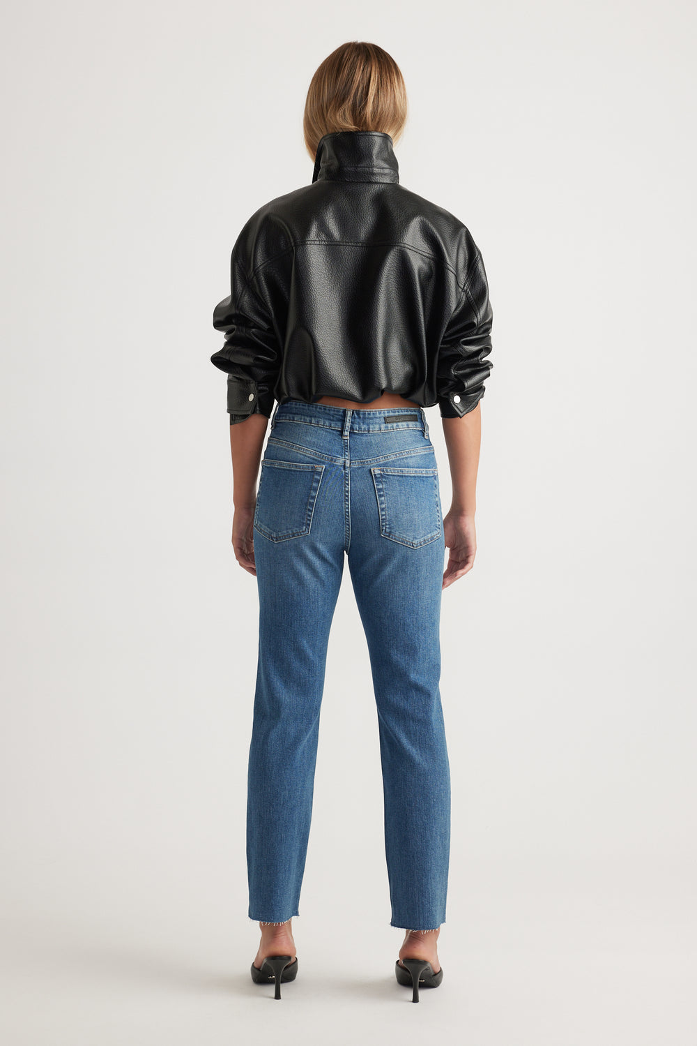 Rear view of Becky Straight Leg Jean in classic blue denim styled with black faux leather jacket by Decjuba Australian fashion brand