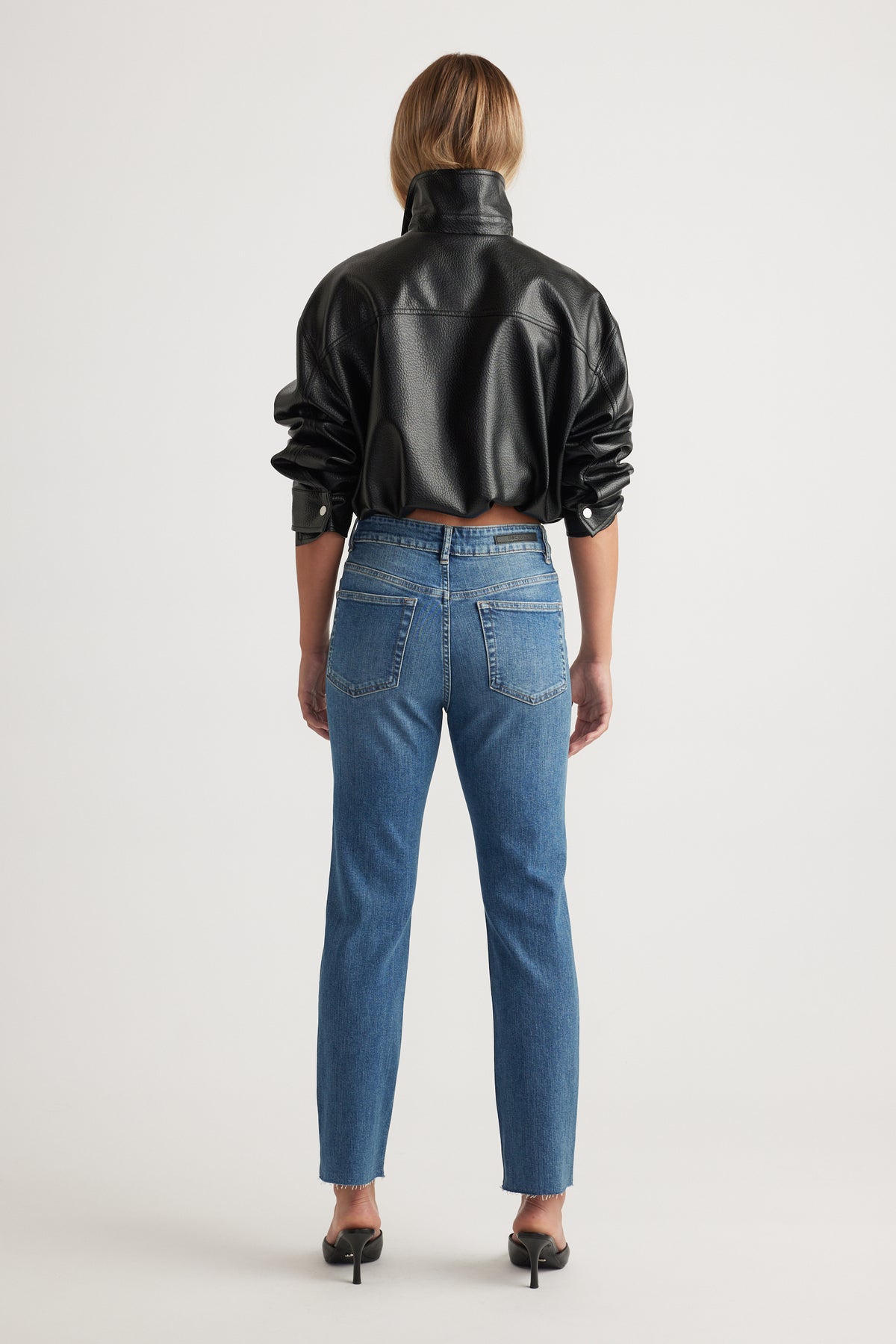 Rear view of Becky Straight Leg Jean in classic blue denim styled with black faux leather jacket by Decjuba Australian fashion brand