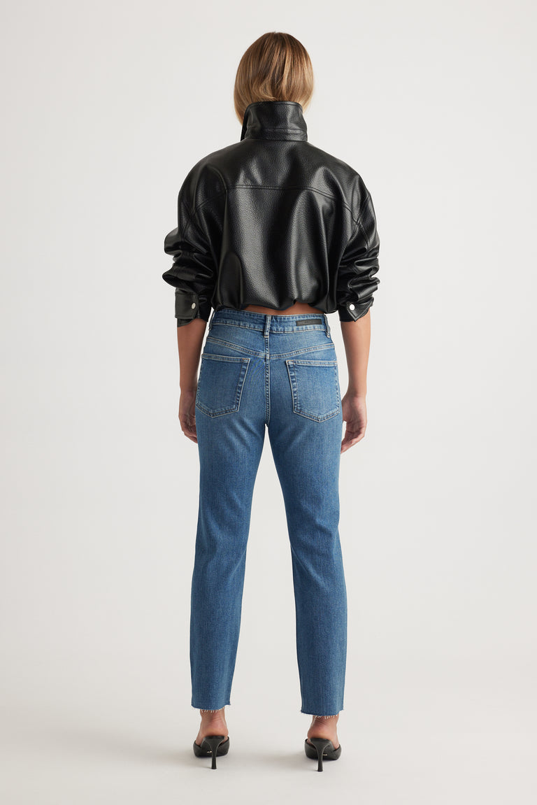 Rear view of Becky Straight Leg Jean in classic blue denim styled with black faux leather jacket by Decjuba Australian fashion brand