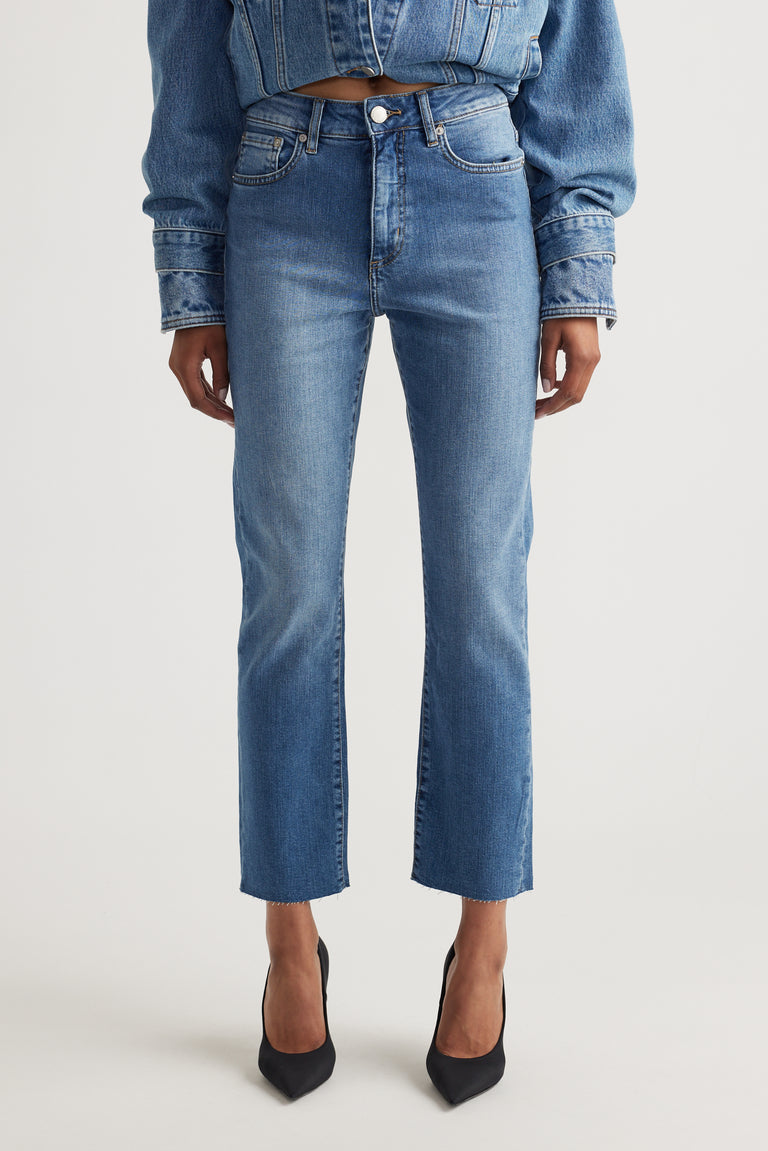 Front view of mid-rise straight-leg blue denim jeans styled with a cropped denim jacket and black pointed heels