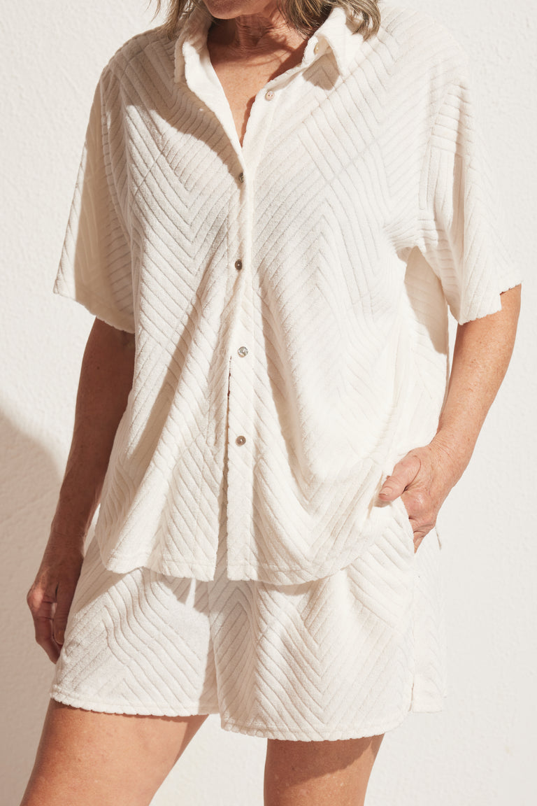 Woman wearing relaxed cream textured terry shirt and matching shorts with pockets, styled for effortless everyday comfort