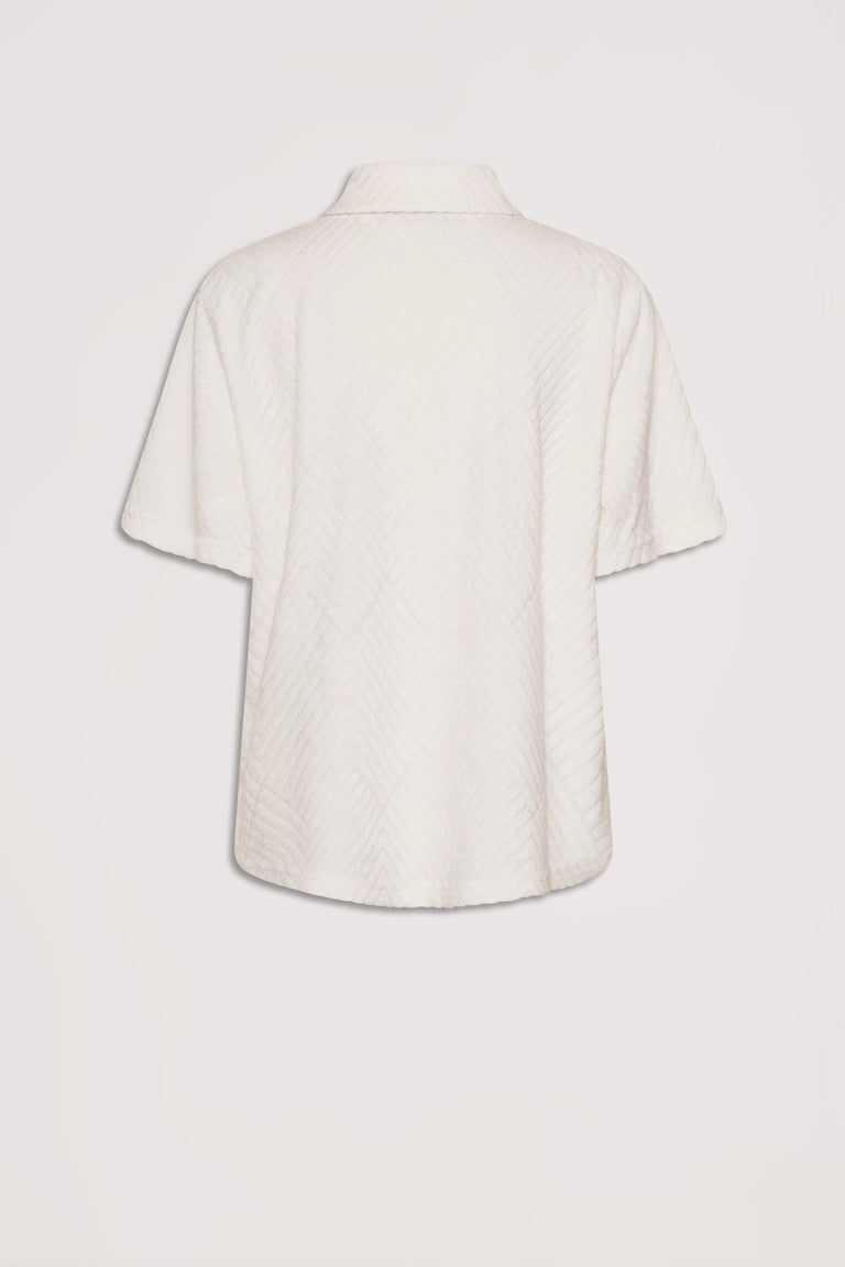 Back view of a short-sleeve terry shirt in a soft vanilla shade with subtle textured patterning.