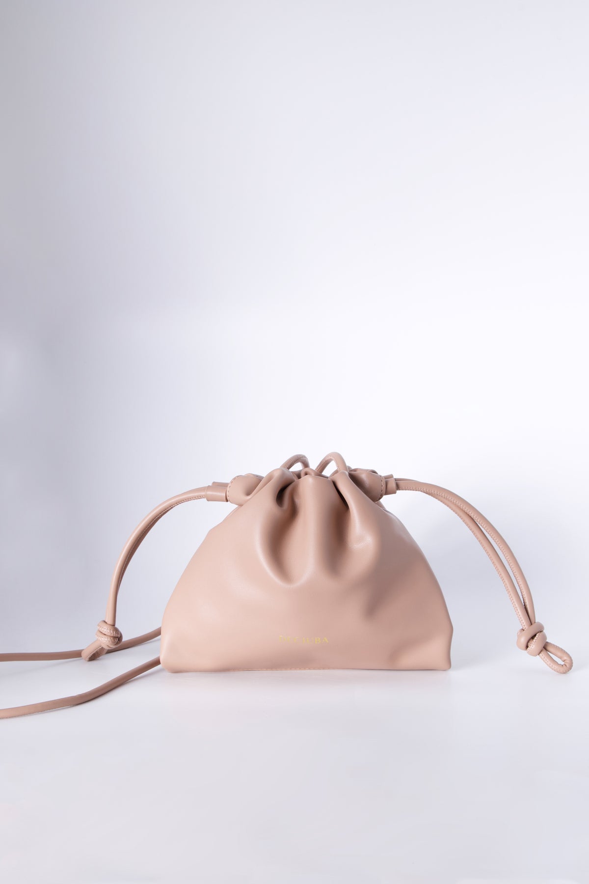 Blush drawstring sling bag with a thin strap and gathered closure