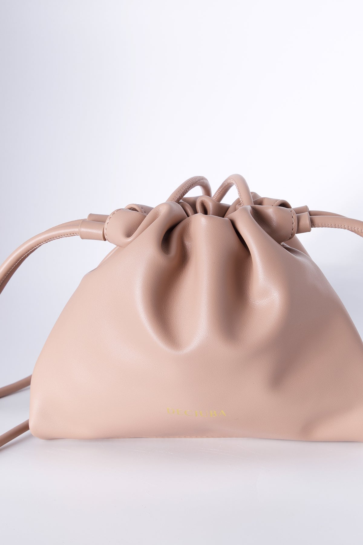 Blush pink drawstring sling bag with a thin strap and subtle front logo