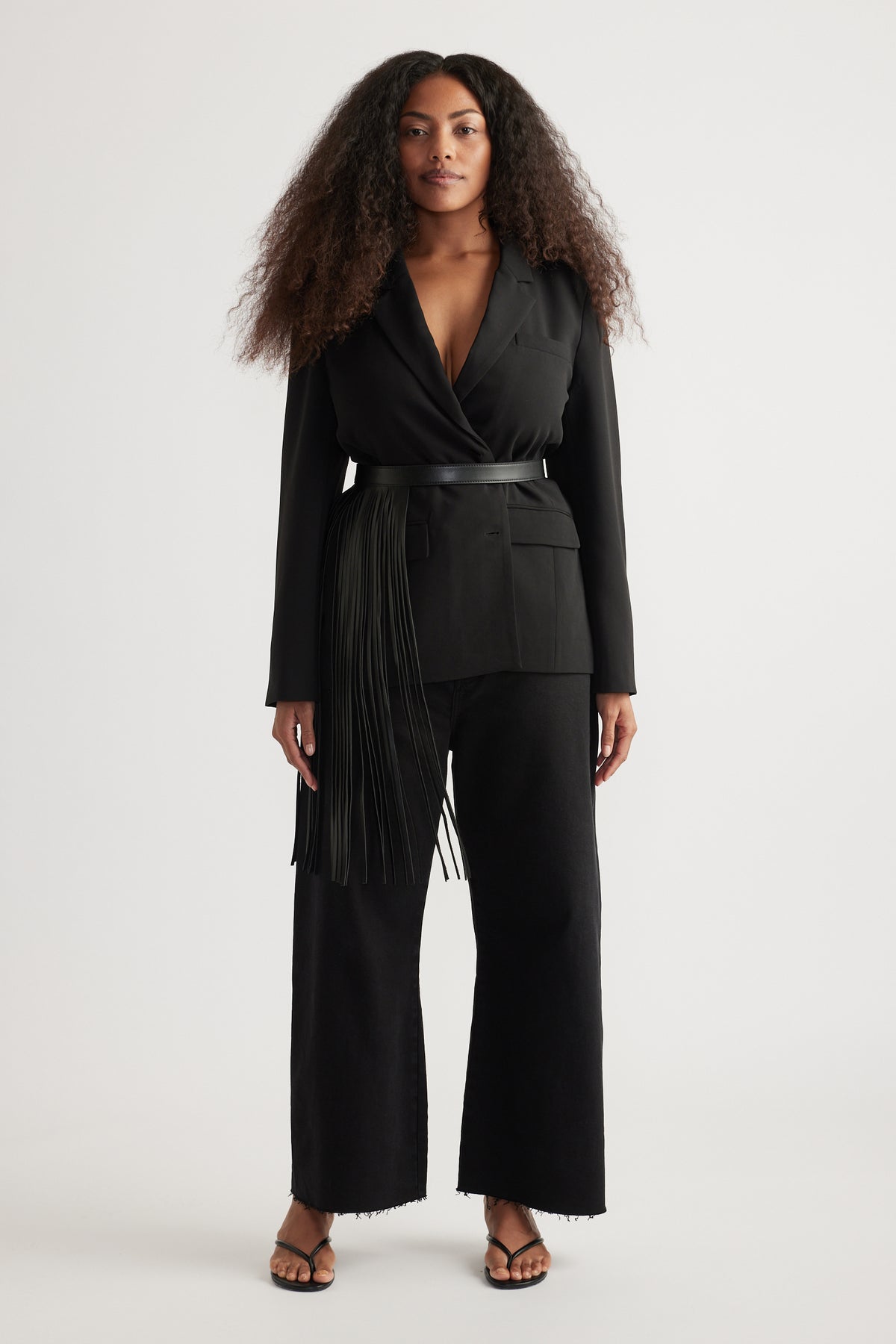 Woman wearing an oversized black tailored blazer with peak lapels, belted waist and wide-leg pants