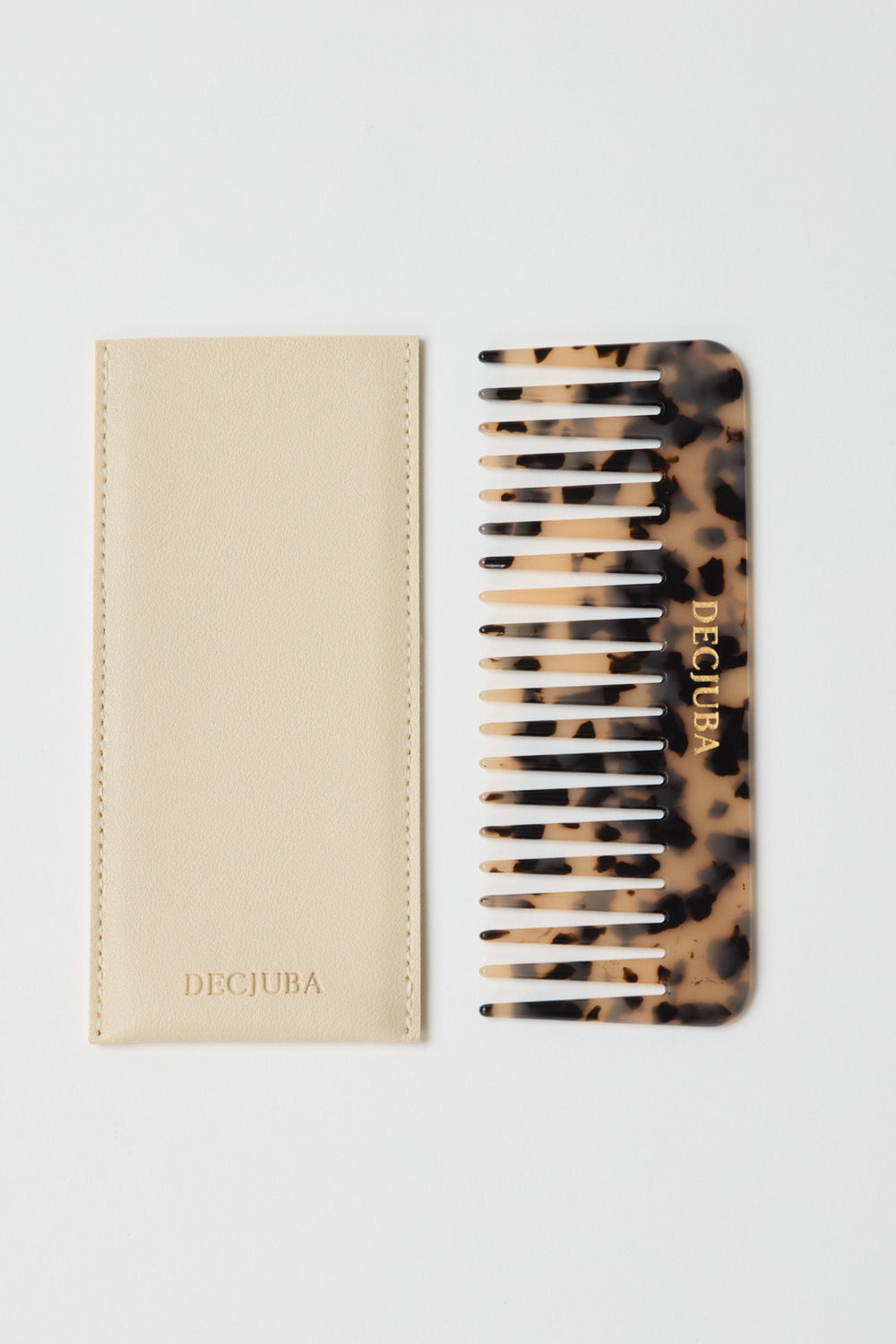 Tortoiseshell patterned wide-tooth comb with gold branding, paired with a cream soft case featuring subtle stitching.