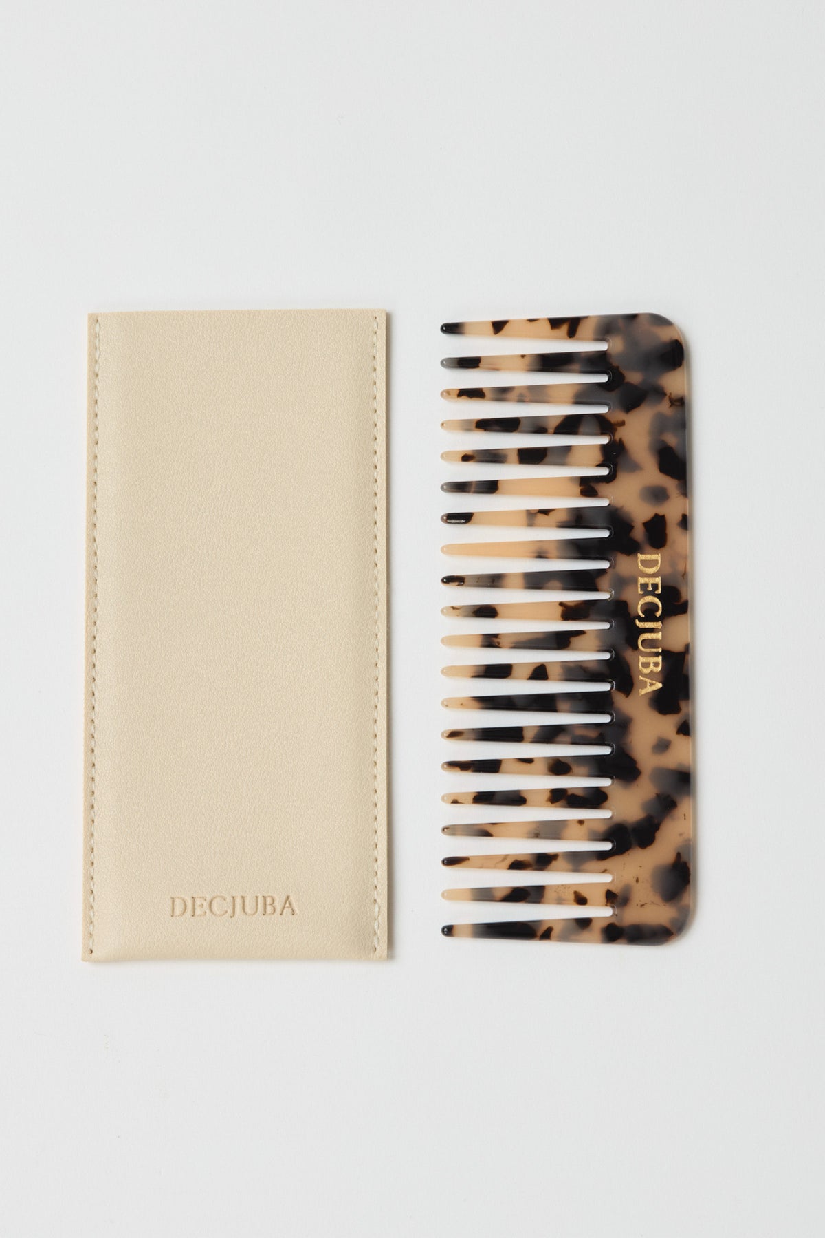 Tortoiseshell patterned wide-tooth comb with gold branding, paired with a cream soft case featuring subtle stitching.