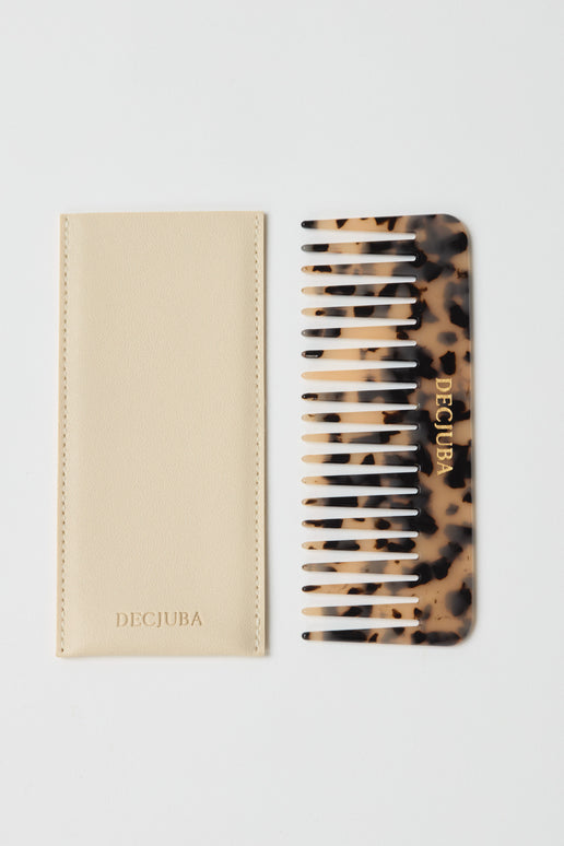 Tortoiseshell patterned wide-tooth comb with gold branding, paired with a cream soft case featuring subtle stitching.