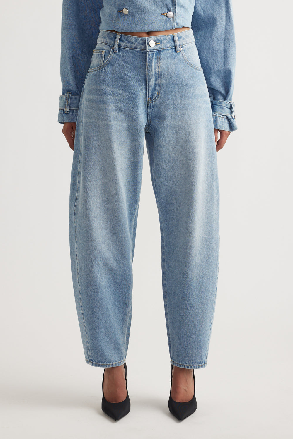 Light wash barrel leg jeans styled with black pointed heels and a matching cropped denim jacket