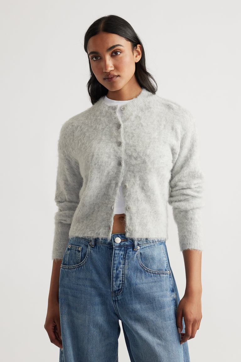 Light grey fluffy cardigan with button front, ribbed cuffs, and a soft, cozy texture paired with classic blue jeans.
