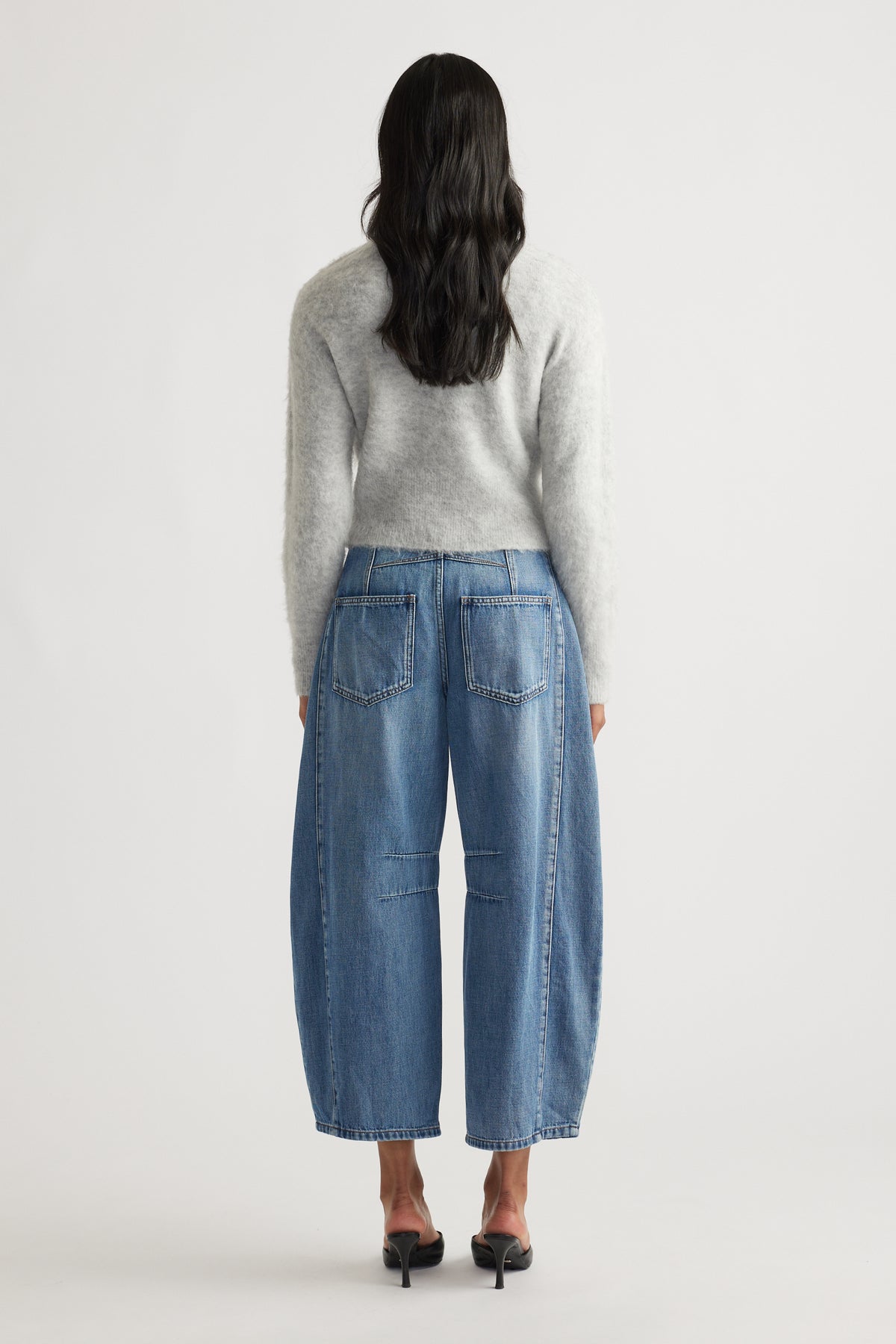 Back view of light grey fluffy cardigan paired with wide-leg cropped blue jeans and black heeled sandals