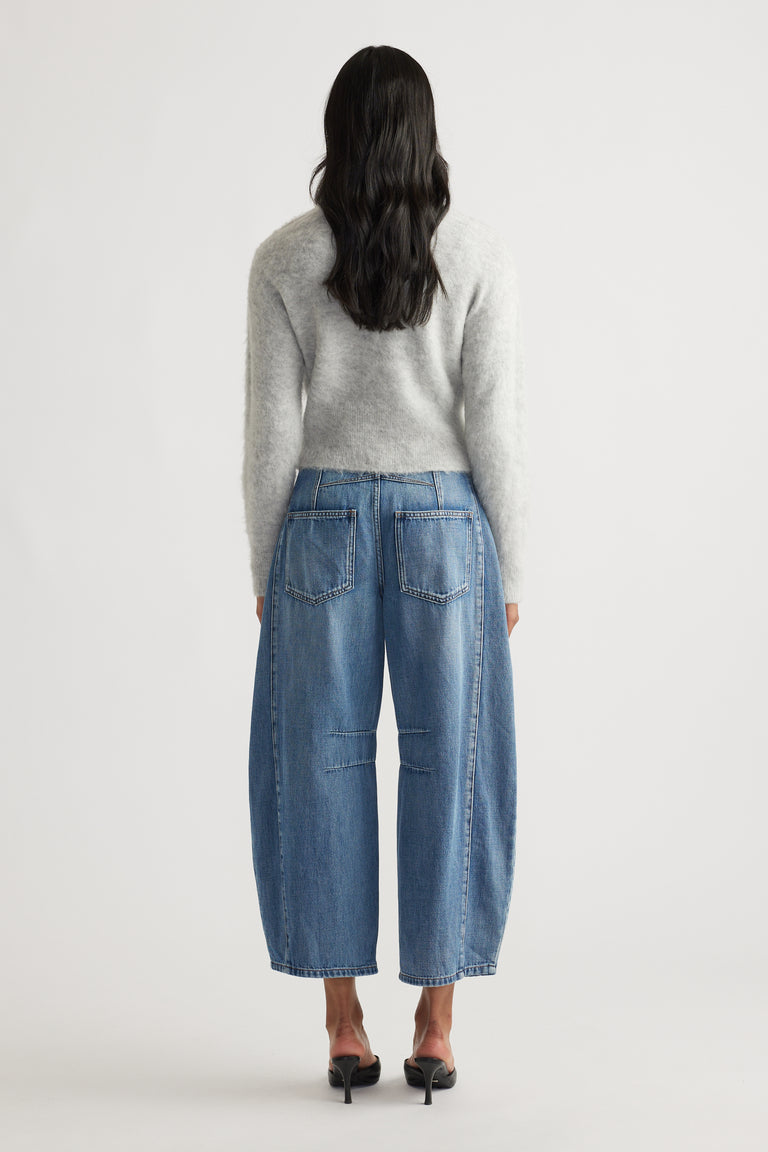 Back view of light grey fluffy cardigan paired with wide-leg cropped blue jeans and black heeled sandals