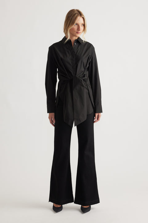 Woman wearing a sleek black tie-front shirt paired with high-waisted flared pants and pointed heels
