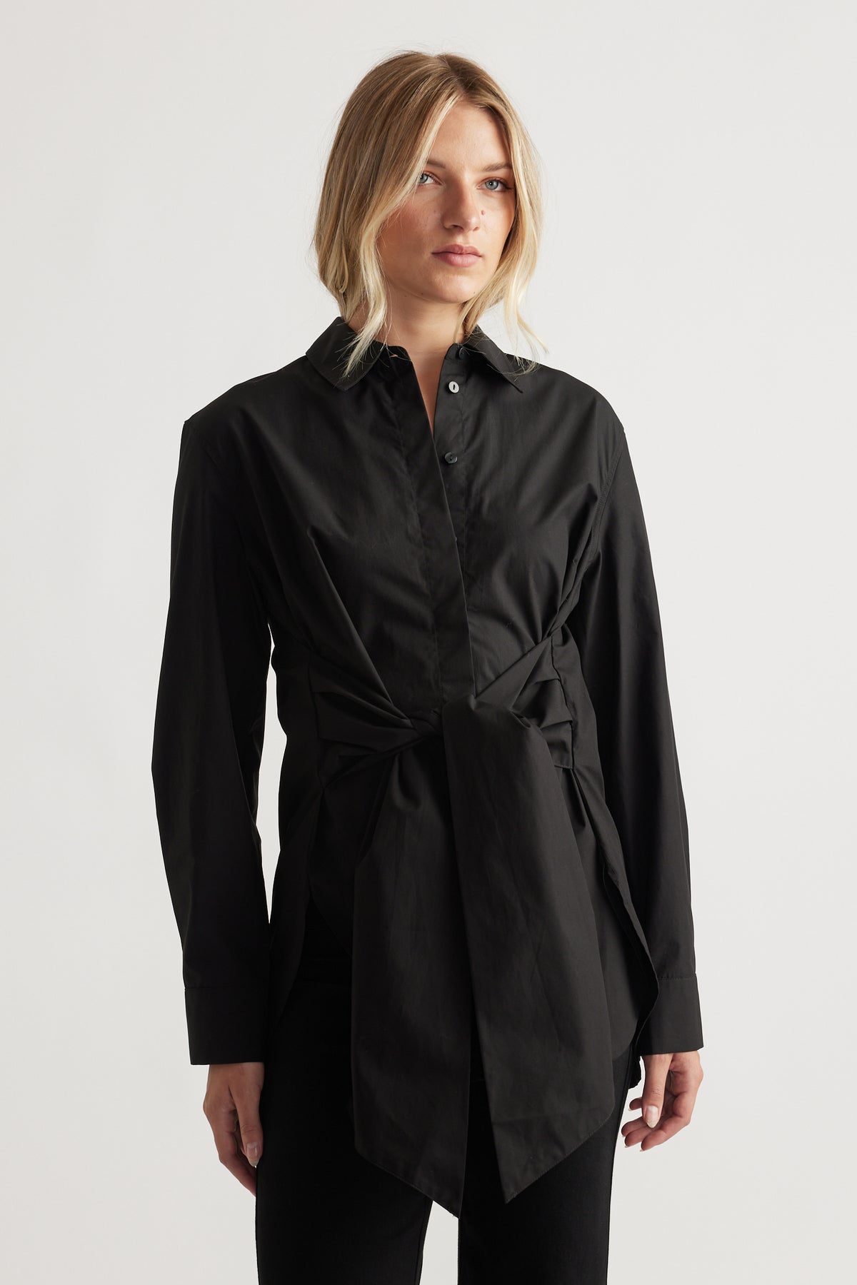 Woman wearing a black tie-front shirt with a structured collar and long sleeves for polished everyday style