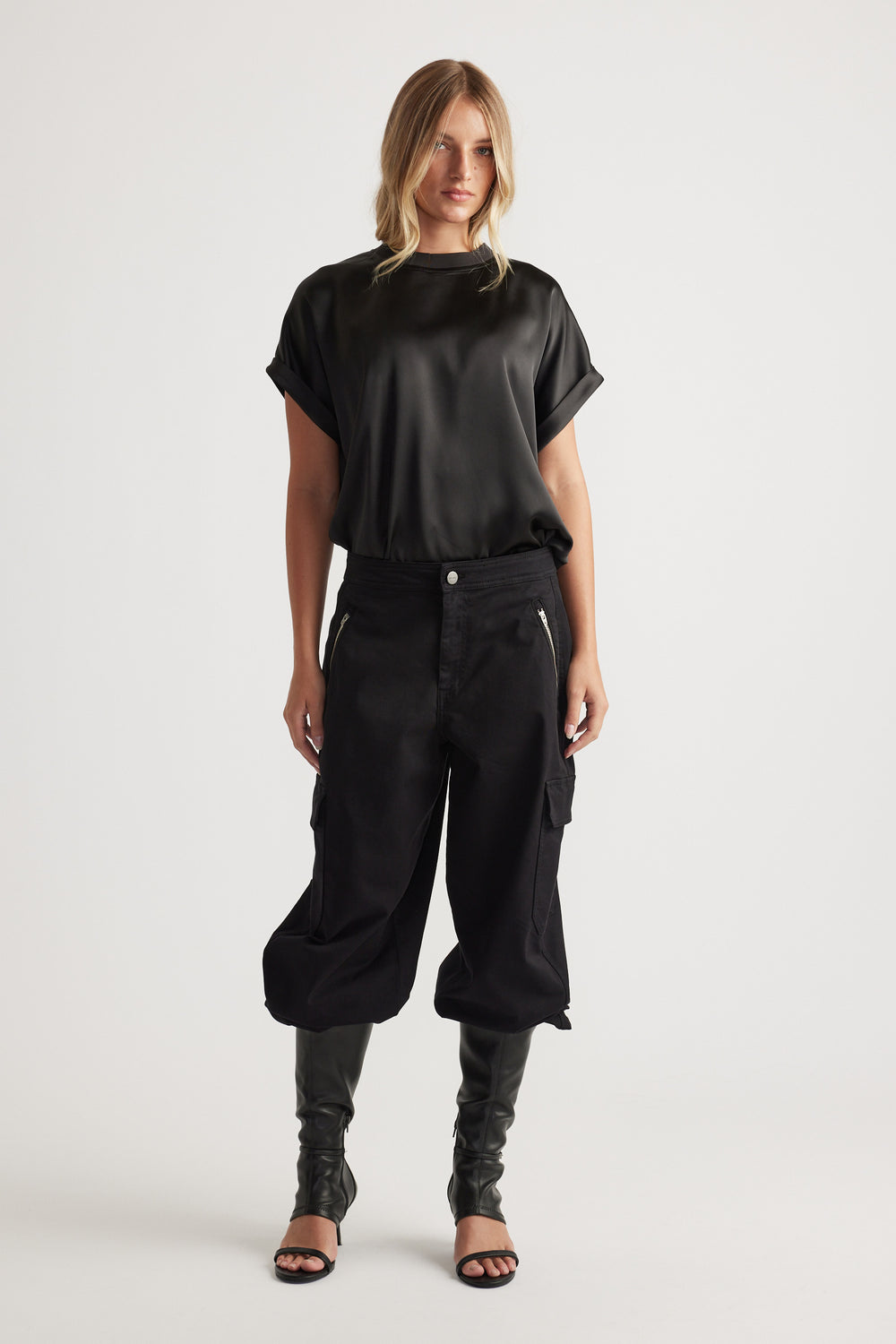 Woman wearing AnnMaree Satin Tee in black styled with relaxed cargo pants and black open-toe heels for modern casual look.