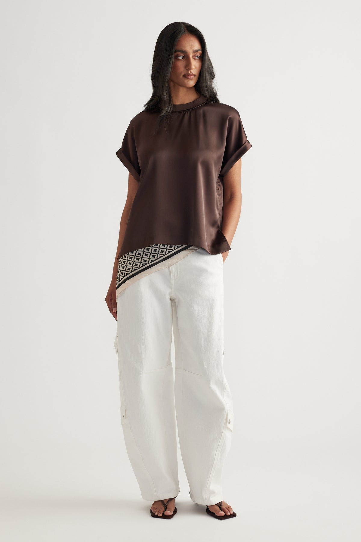 Woman wearing a brown satin tee with white pants