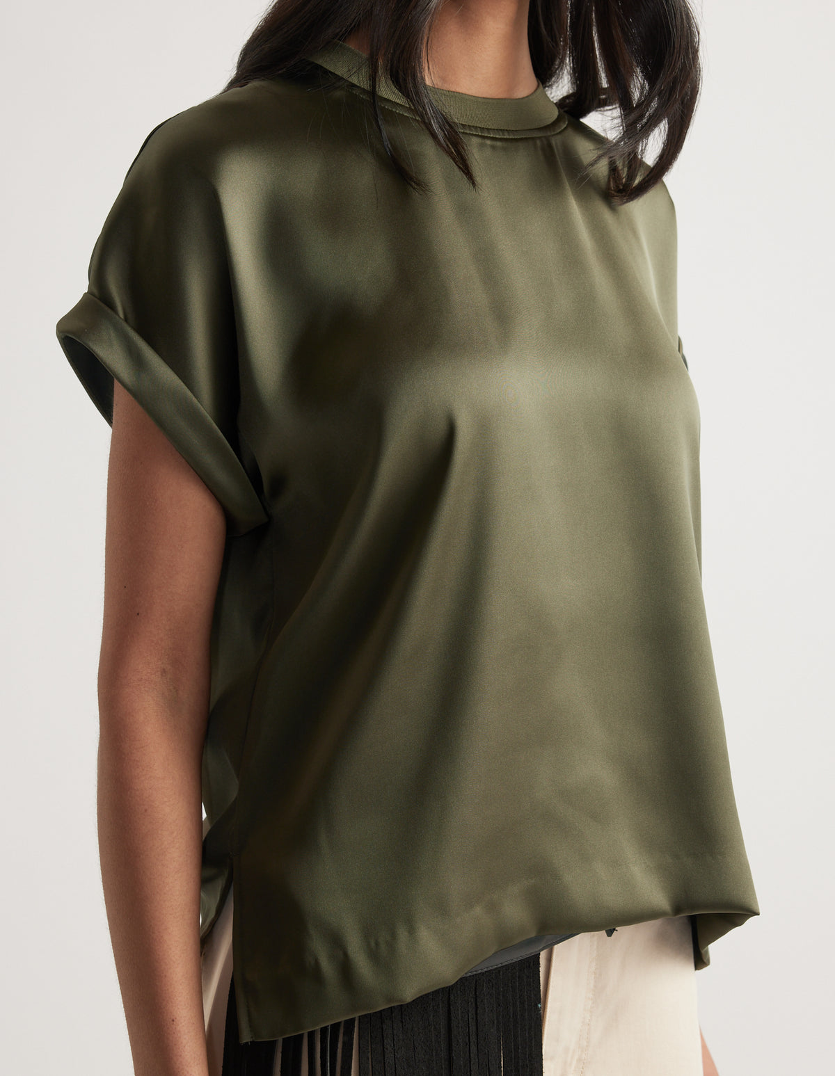Woman wearing a relaxed fit olive green satin short sleeve top with rolled cuffs and a round neckline