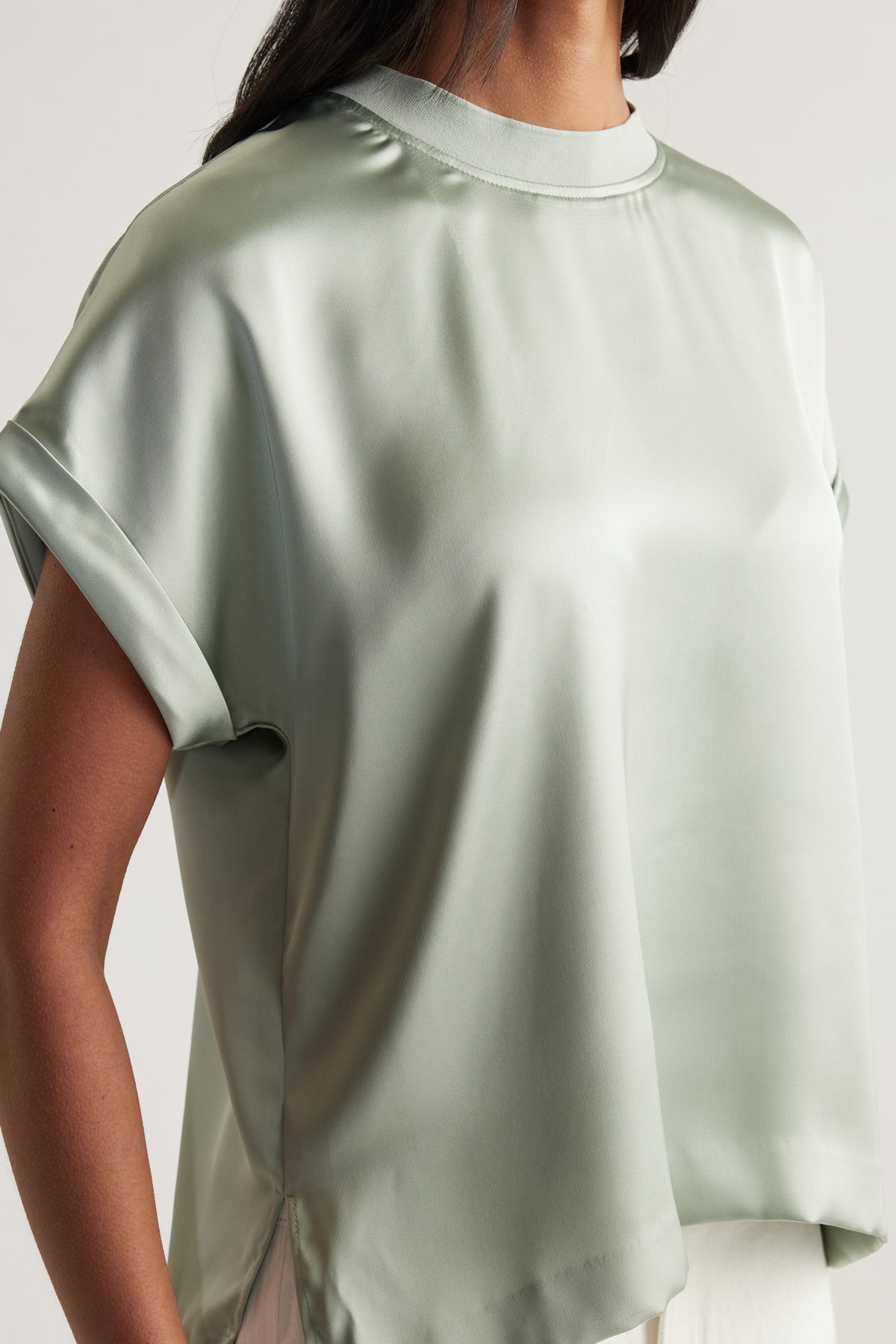 Woman wearing a sage green satin tee with a crew neck, short sleeves and relaxed fit