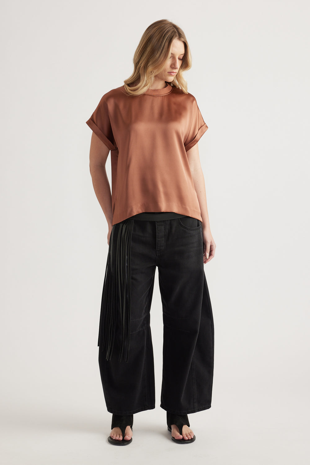 Woman wearing a brown satin short-sleeve tee with black wide-leg pants and sandals