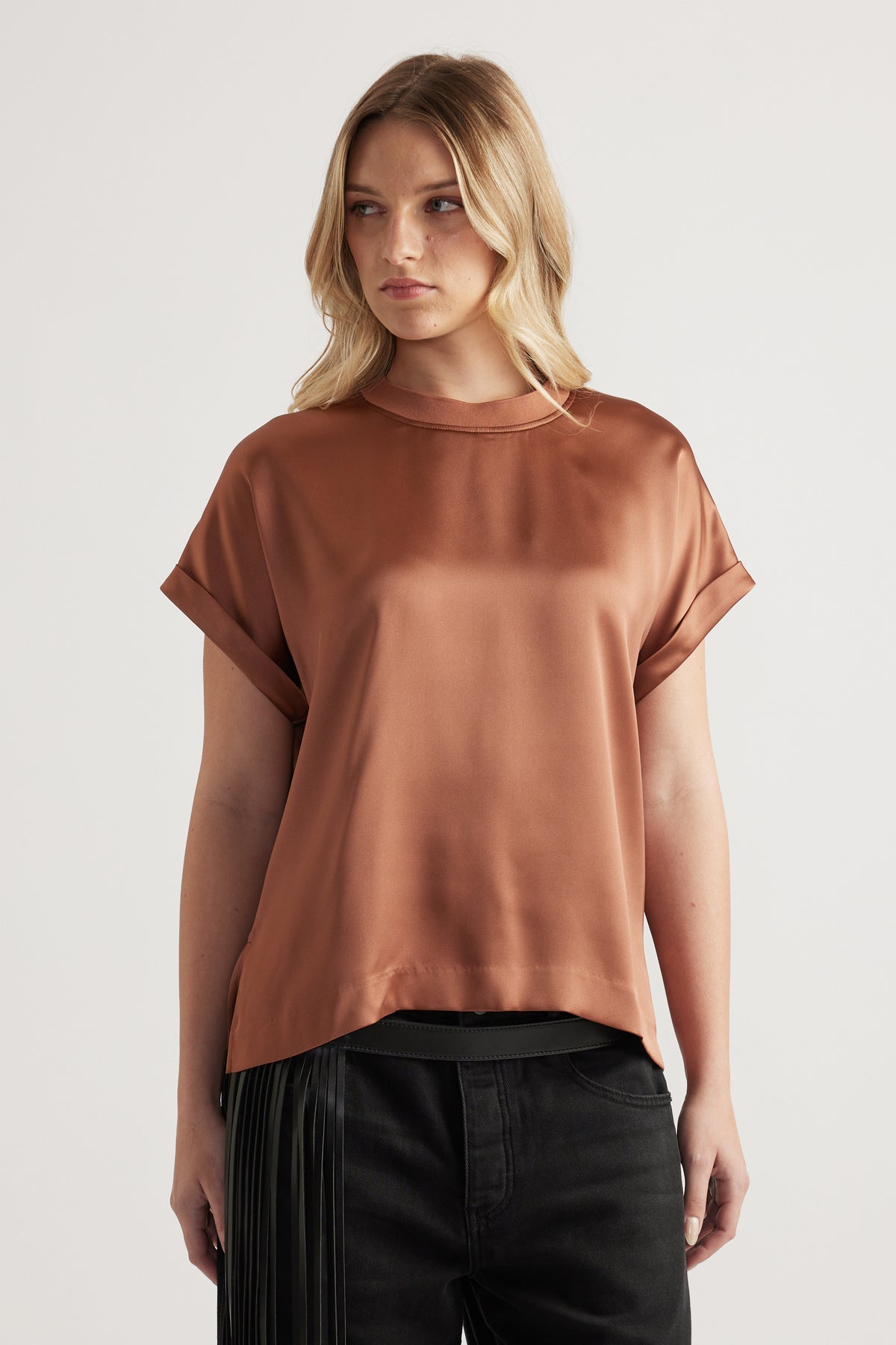Woman wearing a brown satin crew neck tee with rolled sleeves and black jeans