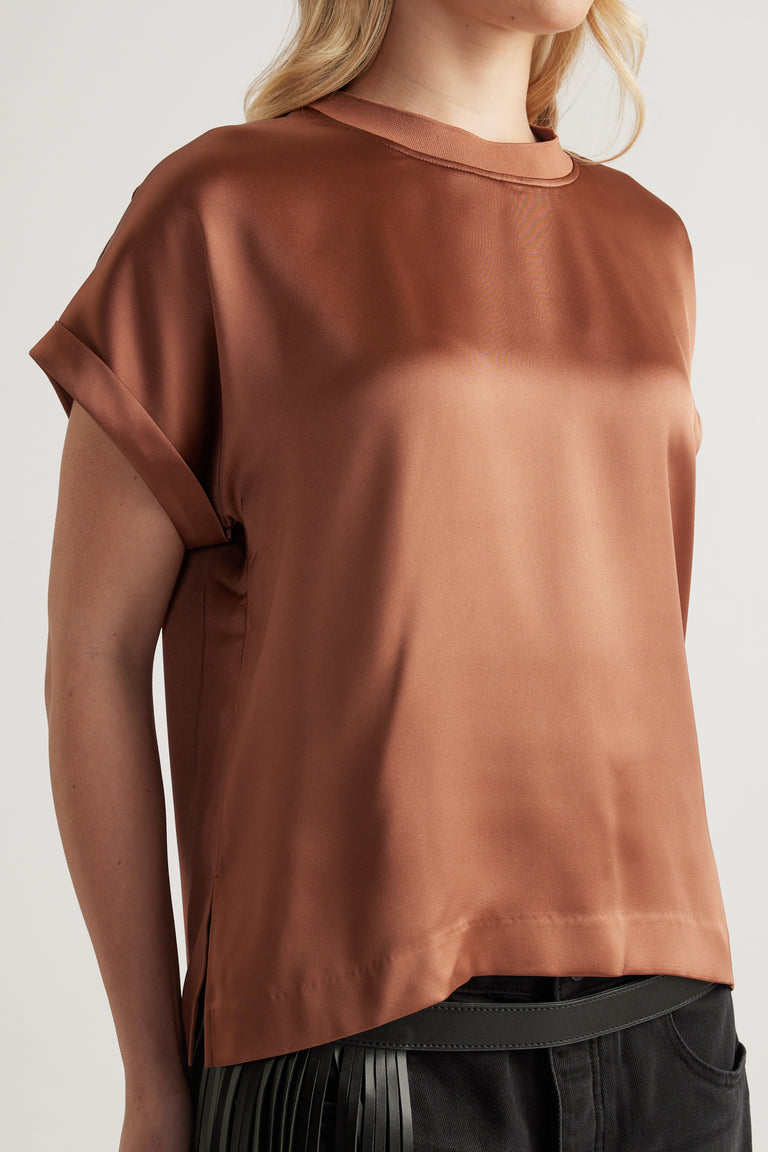 Woman wearing a brown satin short sleeve crew neck top with black pants