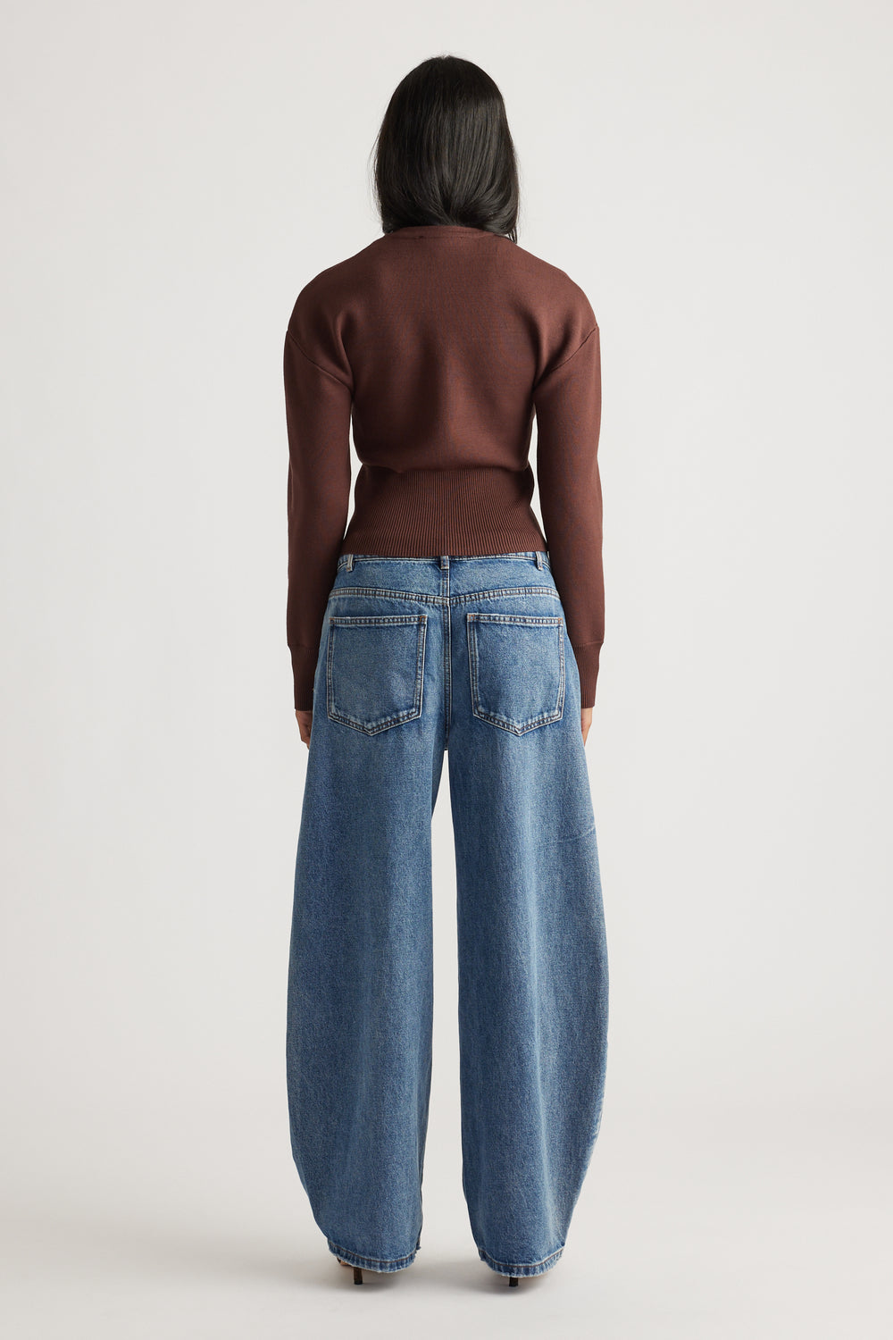 Woman wearing a rich mocha fitted knit cardigan paired with wide-leg mid-blue denim jeans for a casual look