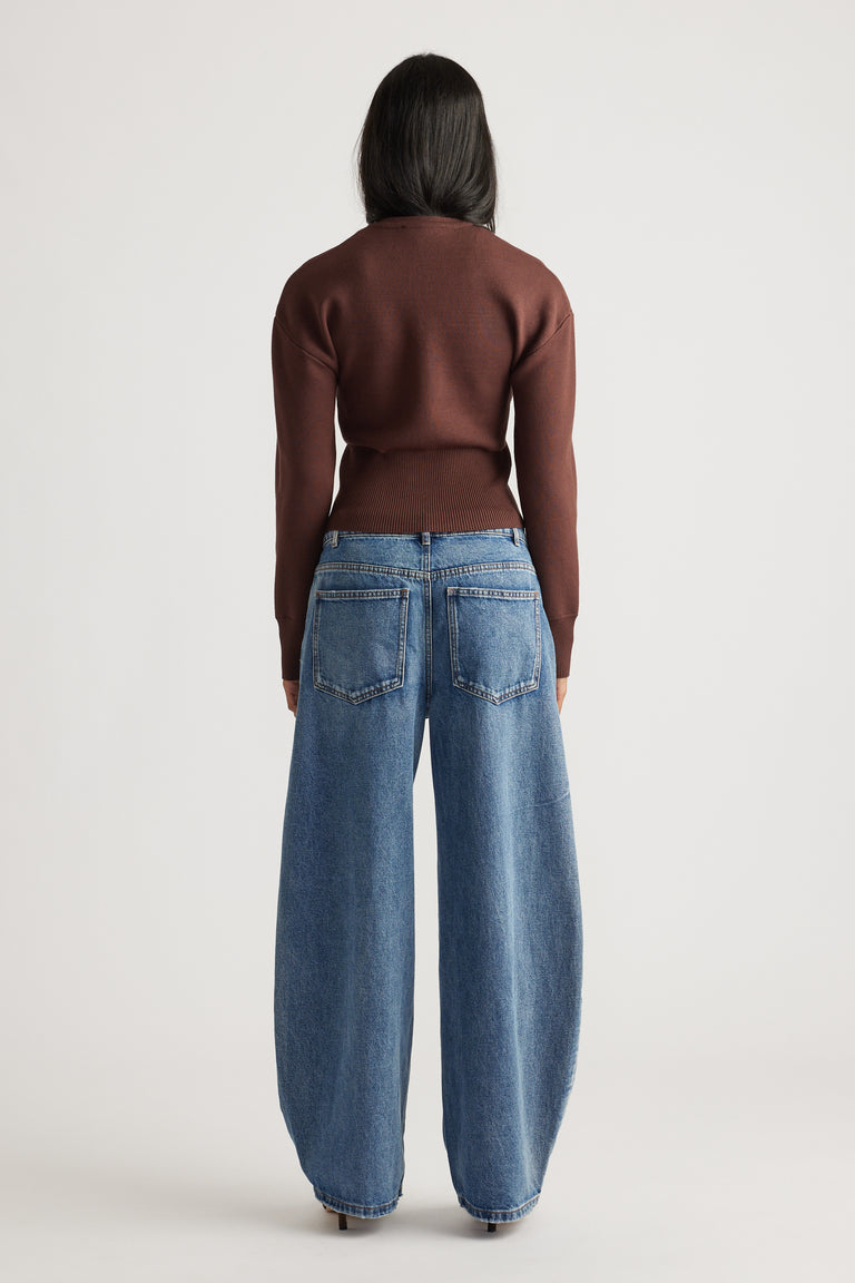 Woman wearing a rich mocha fitted knit cardigan paired with wide-leg mid-blue denim jeans for a casual look