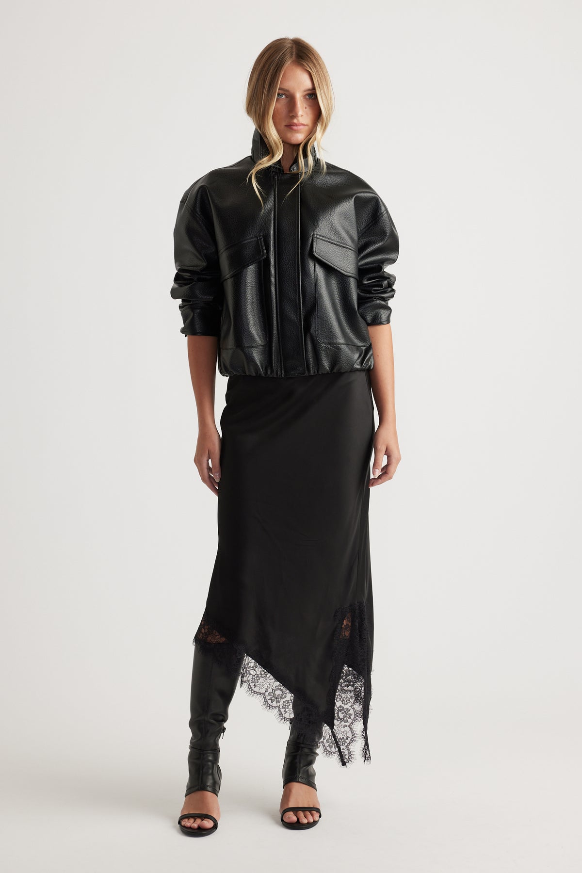 Karla Lace Slip Skirt with lace-trimmed asymmetric hem styled with a black leather jacket and heeled sandals by DECJUBA