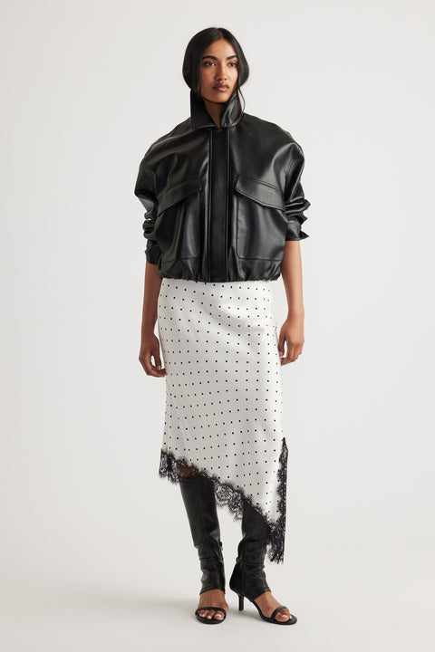 Woman wearing Karla Lace Slip Skirt in ivory with black polka dots and lace trim, paired with black jacket and boots by DECJUBA