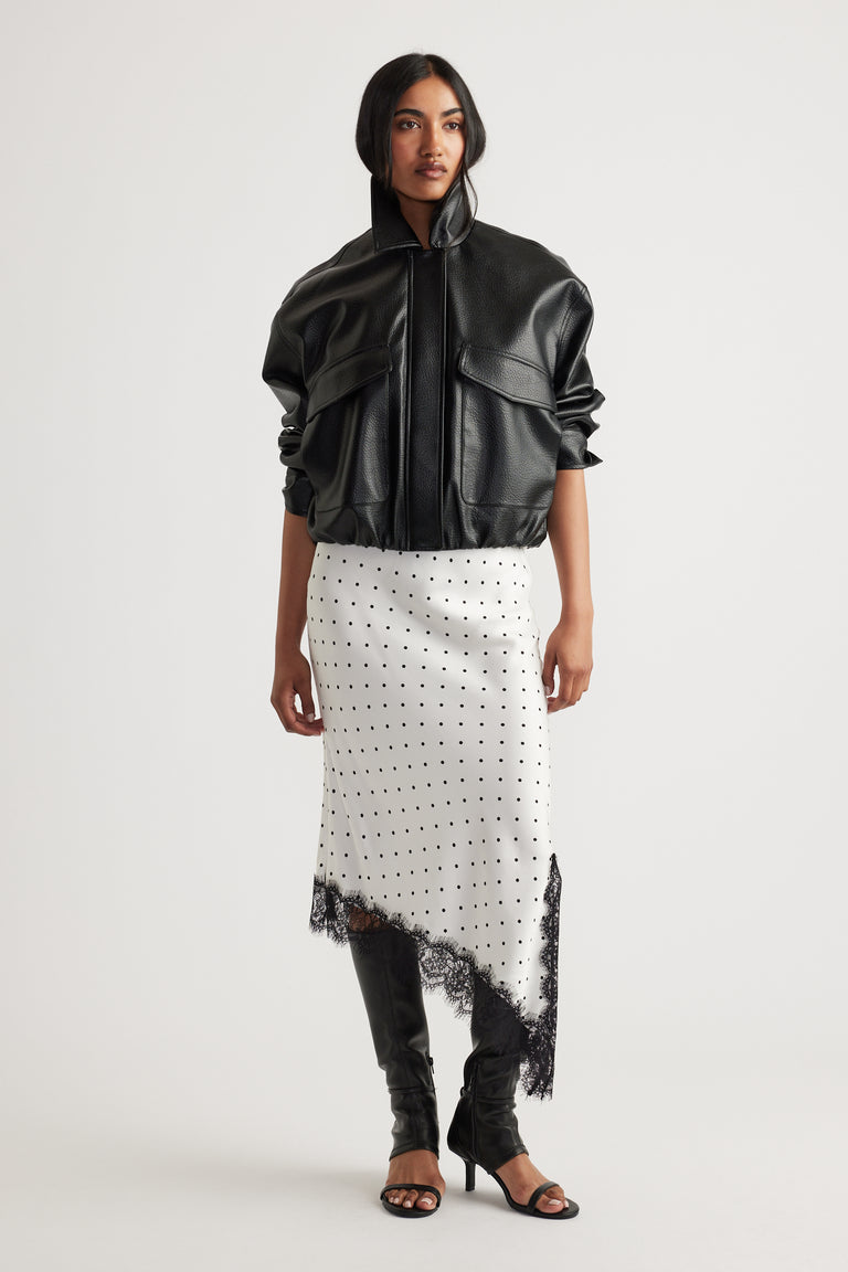 Woman wearing Karla Lace Slip Skirt in ivory with black polka dots and lace trim, paired with black jacket and boots by DECJUBA