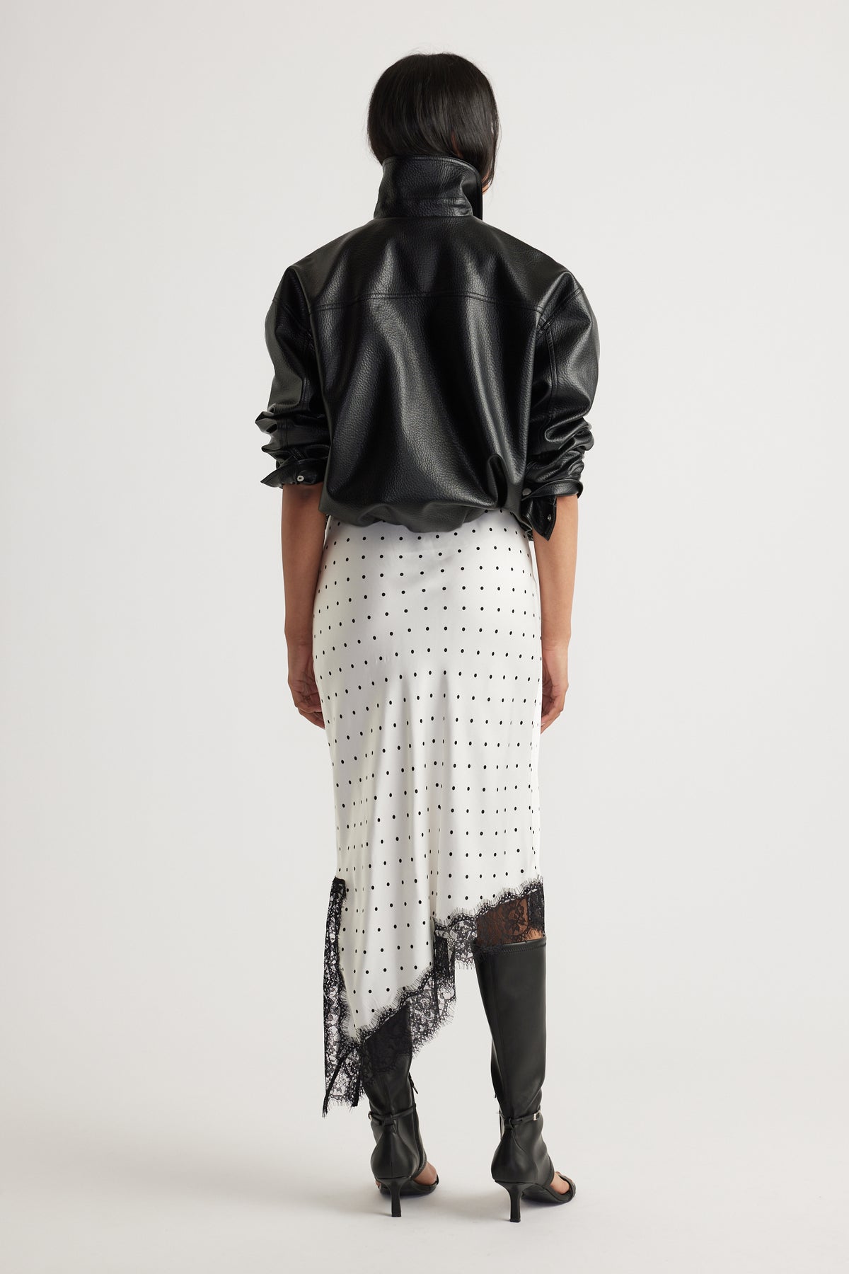 Woman wearing Karla Lace Slip Skirt in ivory with black polka dots and delicate lace trim, styled with black leather jacket and boots
