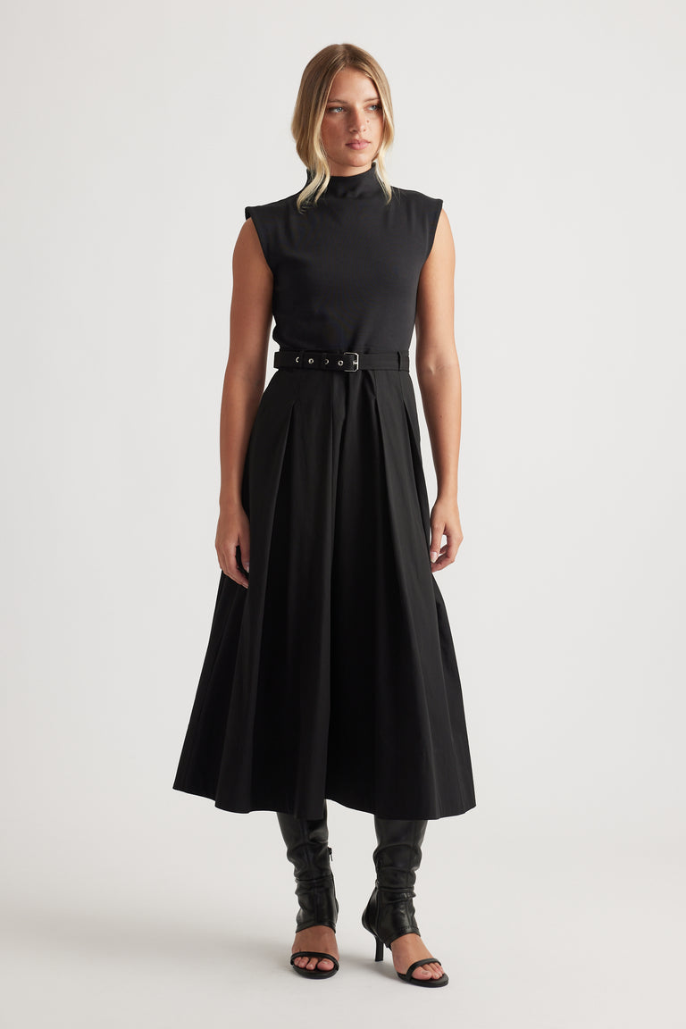 Woman wearing Stefanie Spliced Midi Dress in black with sleeveless top, belted waist, and flowy skirt by DECJUBA