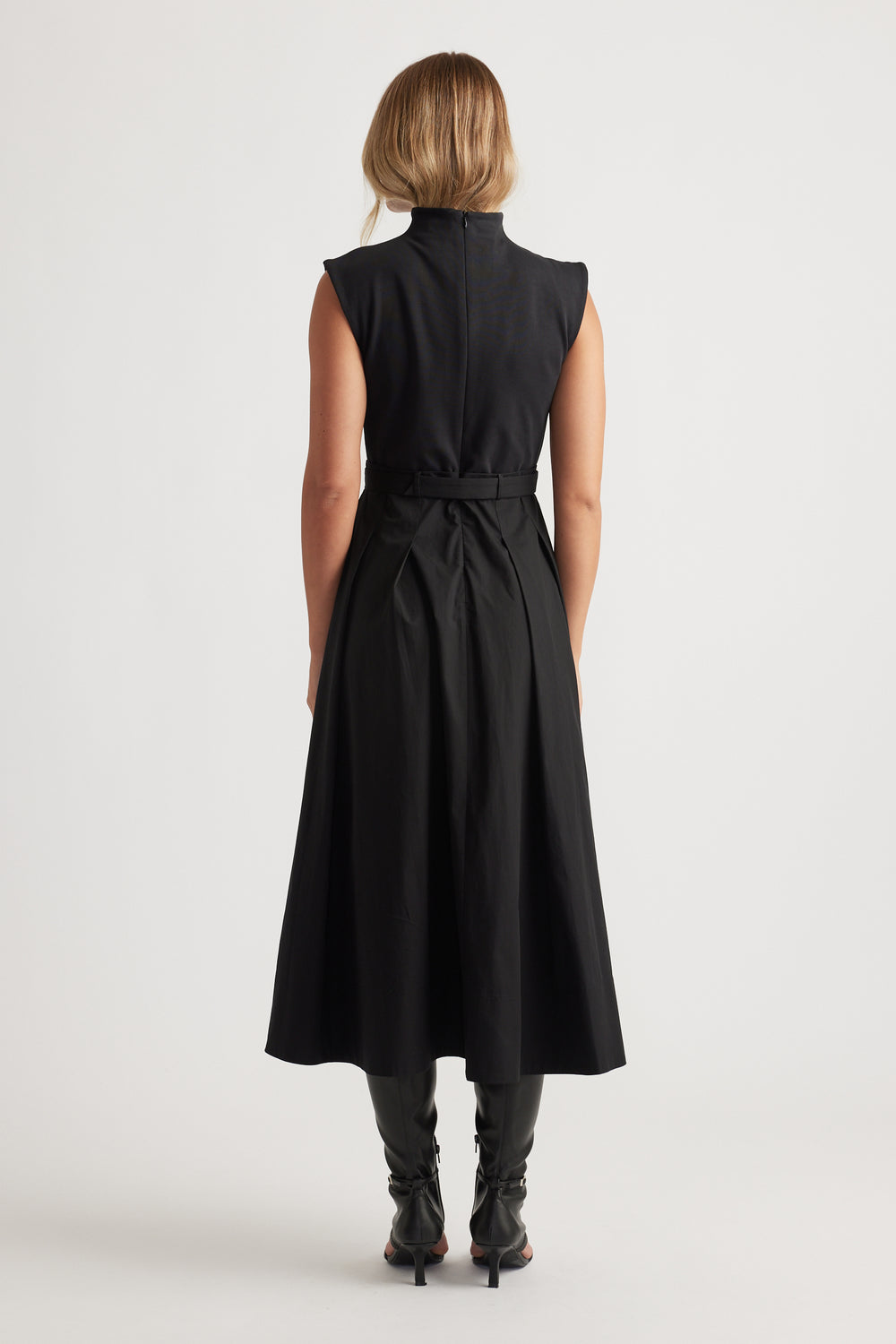 Woman shown from behind wearing sleeveless black Stefanie Spliced Midi Dress with belted waist and pleated skirt by DECJUBA