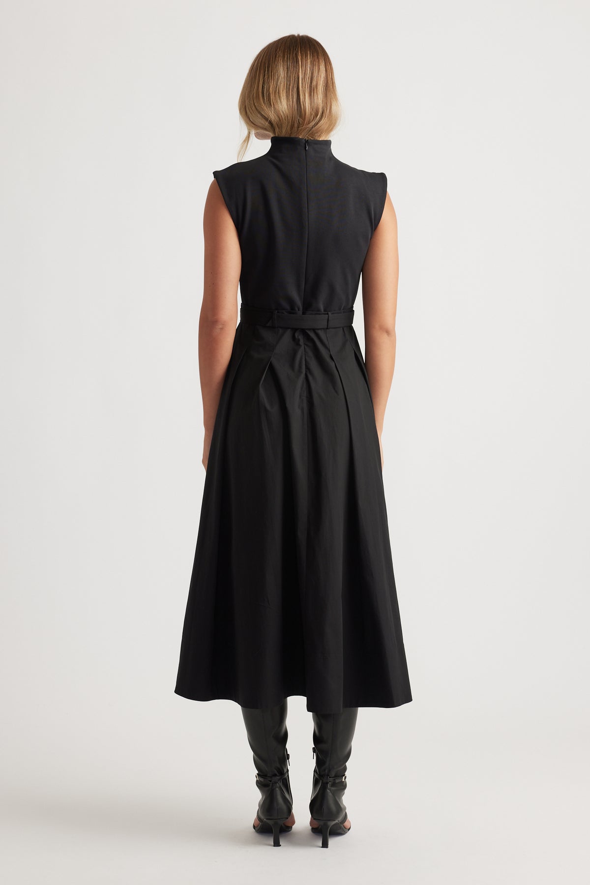 Woman shown from behind wearing sleeveless black Stefanie Spliced Midi Dress with belted waist and pleated skirt by DECJUBA