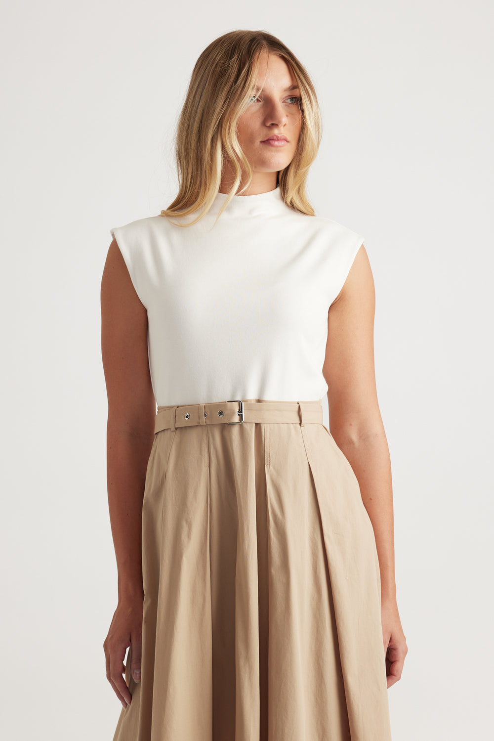 Woman wearing Stefanie Spliced Midi Dress in neutral tones with a belted waist and pleated skirt by DECJUBA.