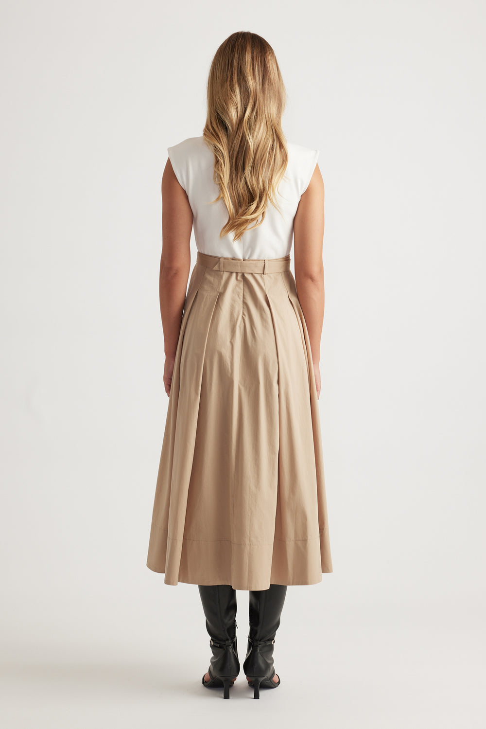 Rear view of Stefanie Spliced Midi Dress in tan with pleated skirt detail and concealed back zipper, styled with black boots