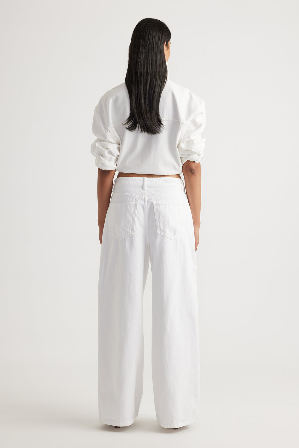 Back view of woman wearing white Elena Wide Leg Jean with high waist and relaxed fit by Decjuba Australian brand