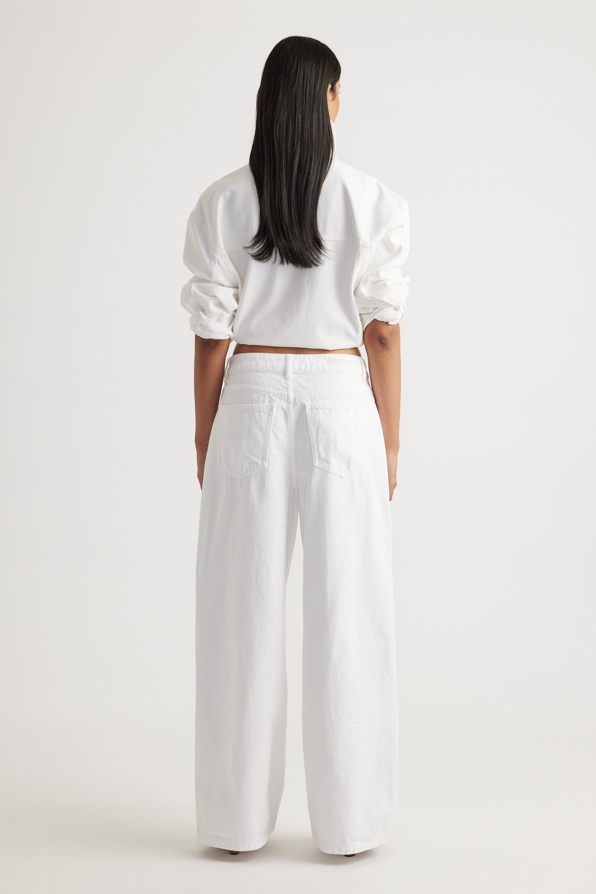 Back view of woman wearing white Elena Wide Leg Jean with high waist and relaxed fit by Decjuba Australian brand