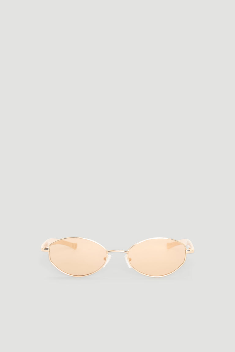 Slim oval sunglasses with gold-toned metal frames and warm beige tinted lenses for a chic, modern look.