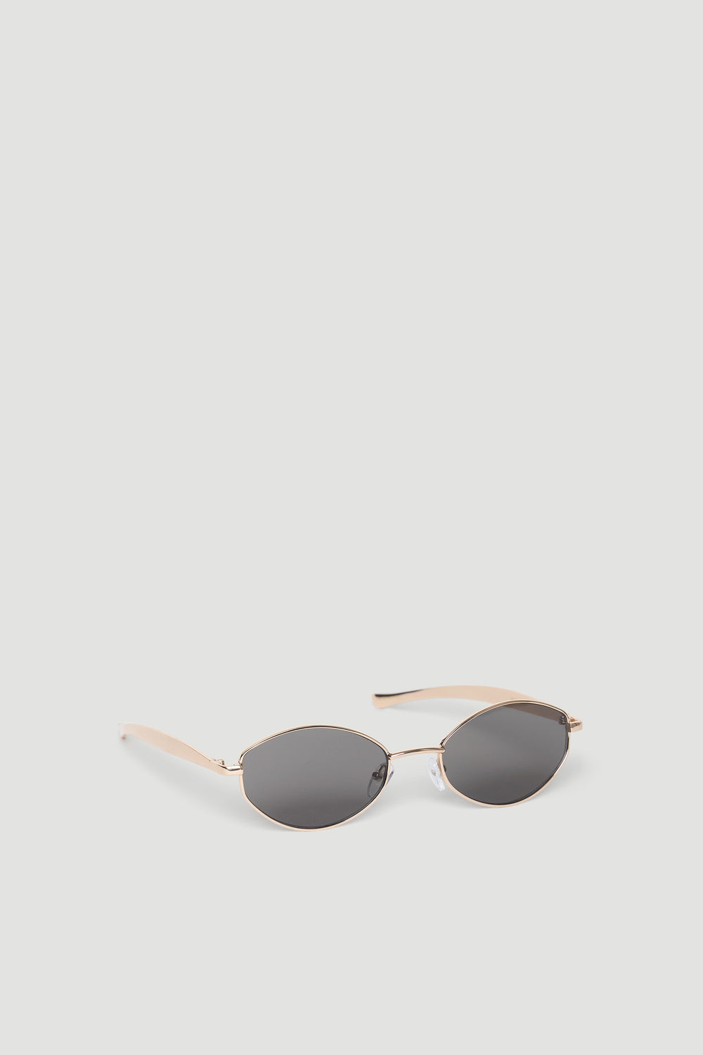 Slim oval sunglasses with gold-tone metal frames and dark tinted lenses for a minimalist, chic look.