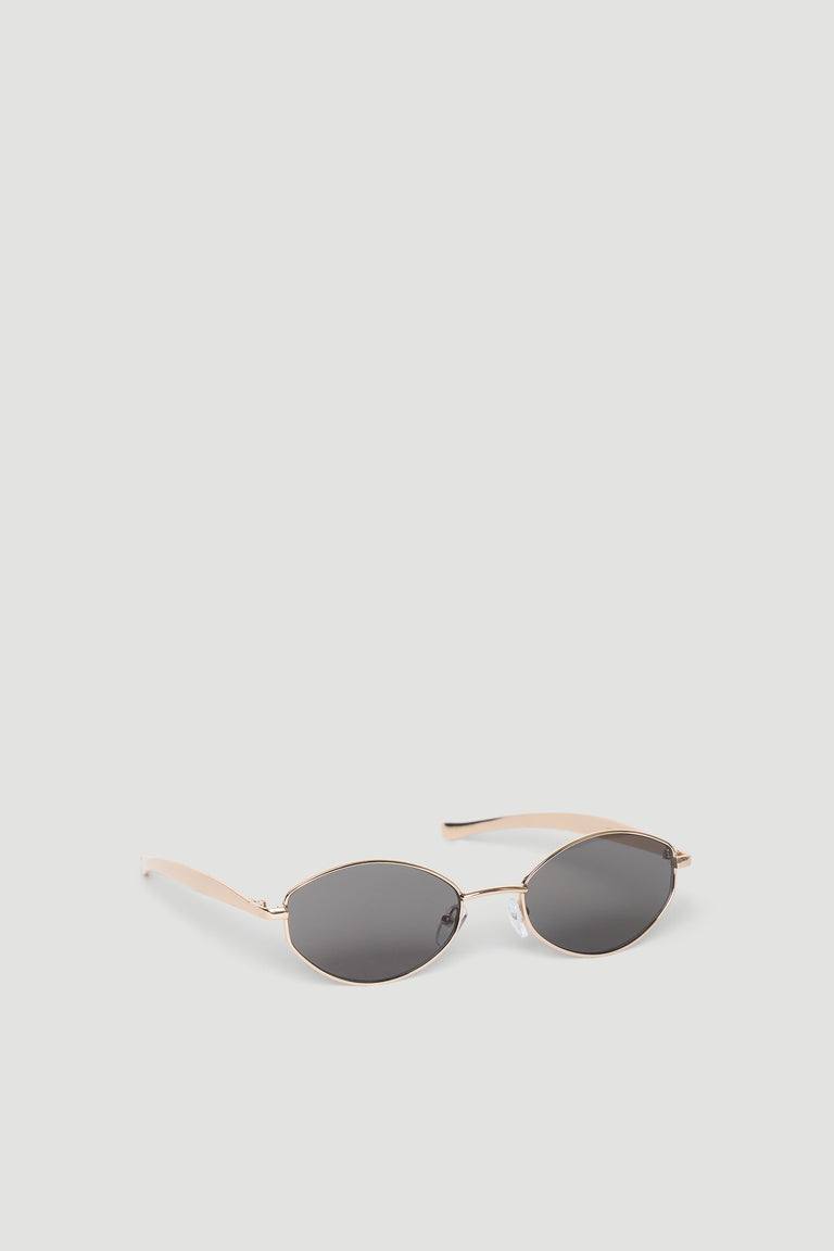 Slim oval sunglasses with gold-tone metal frames and dark tinted lenses for a minimalist, chic look.
