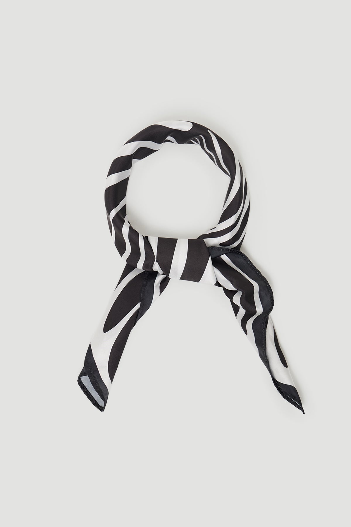 Black and white striped scarf loosely tied in a smooth fabric with a subtle sheen against a light background